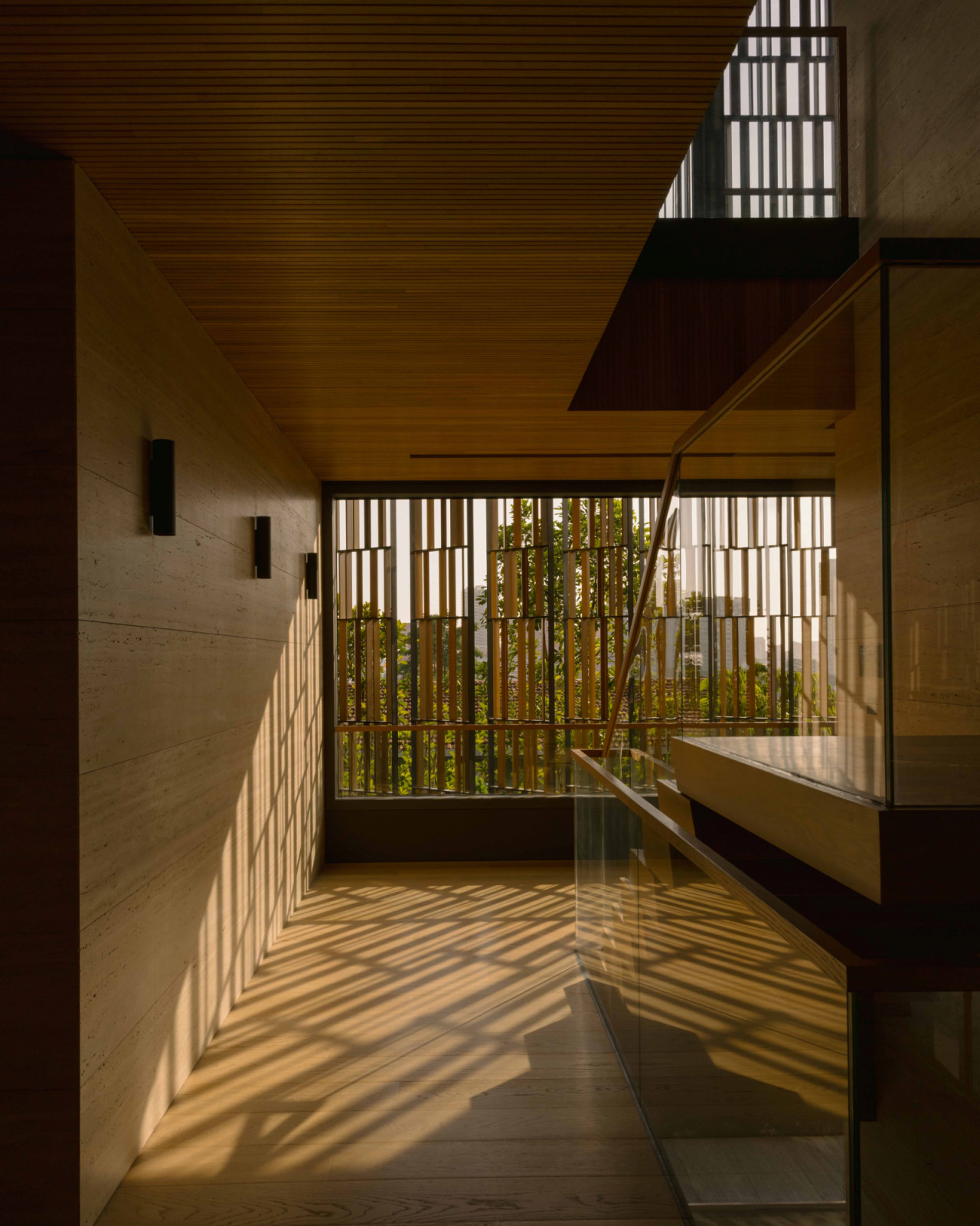 As dusk falls, light weaves through the screened façade, painting the interior with a poetic play of shadows