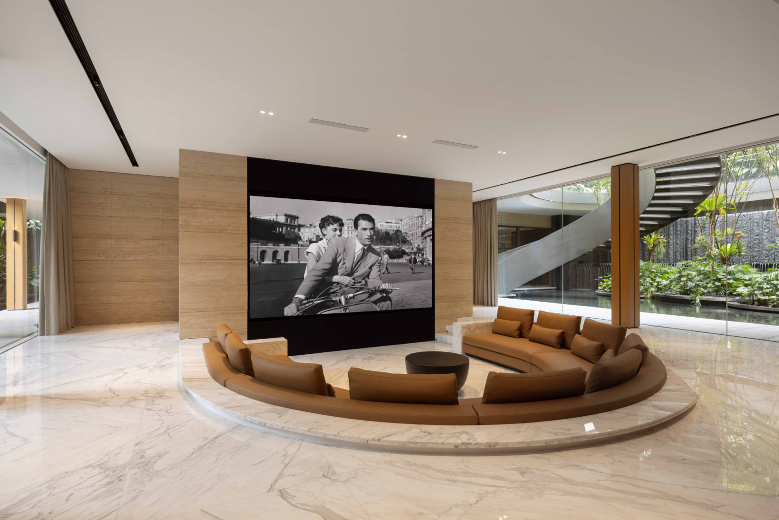 A curving conversation pit forms a cosy, marble-clad private theatre, anchored by a leather-upholstered sofa