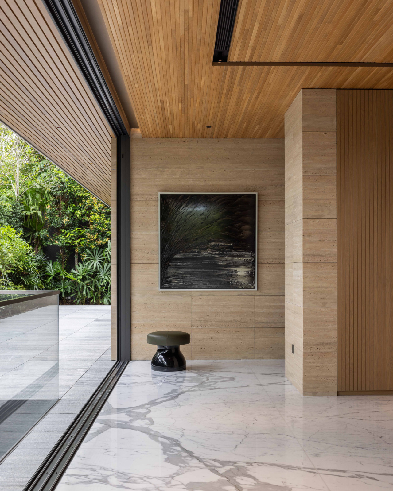A serene architectural corner anchored by a sculptural stool and an artwork
