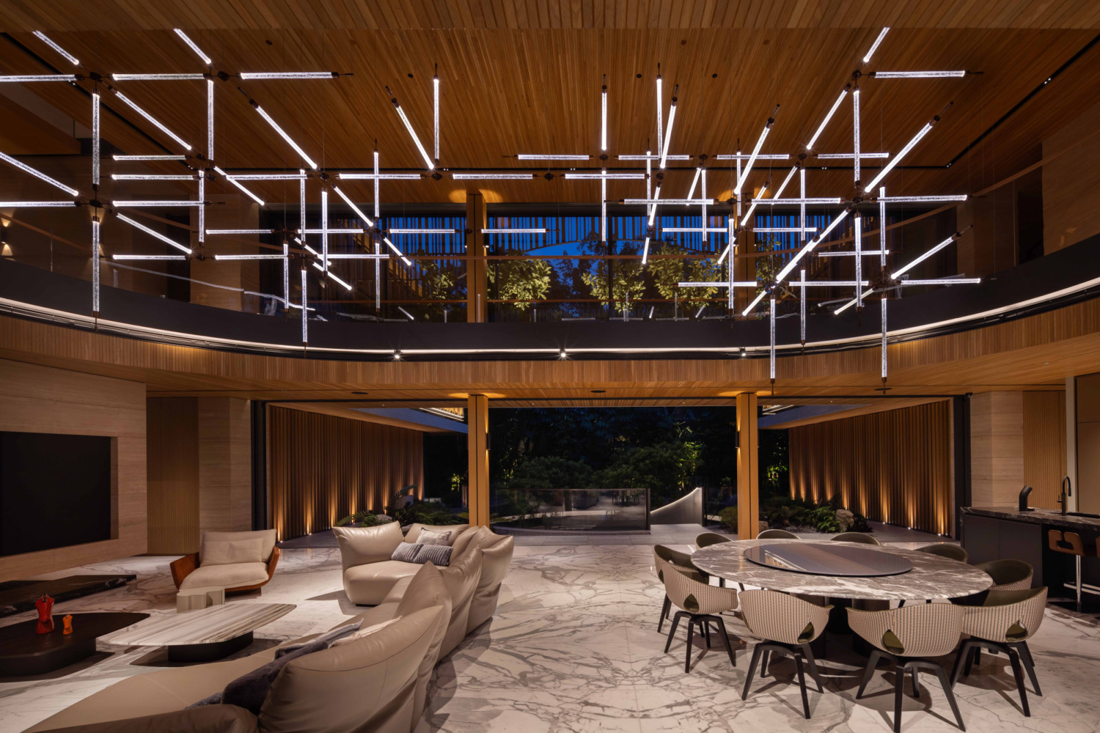 An evening view of the good class bungalow’s open living and dining area, unified by a custom lighting installation from Preciosa