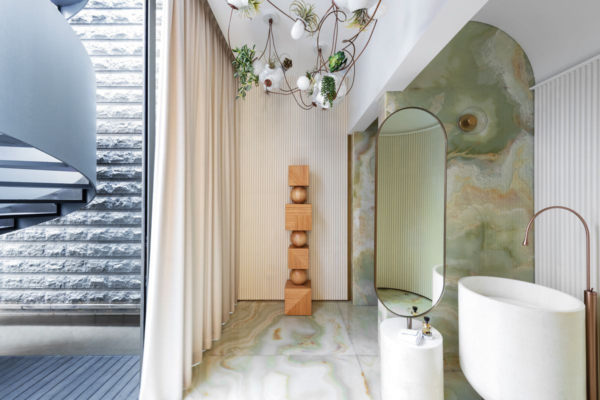 Clad in pale, jade-hued onyx, the basement powder room is a key design highlight with its own outdoor access