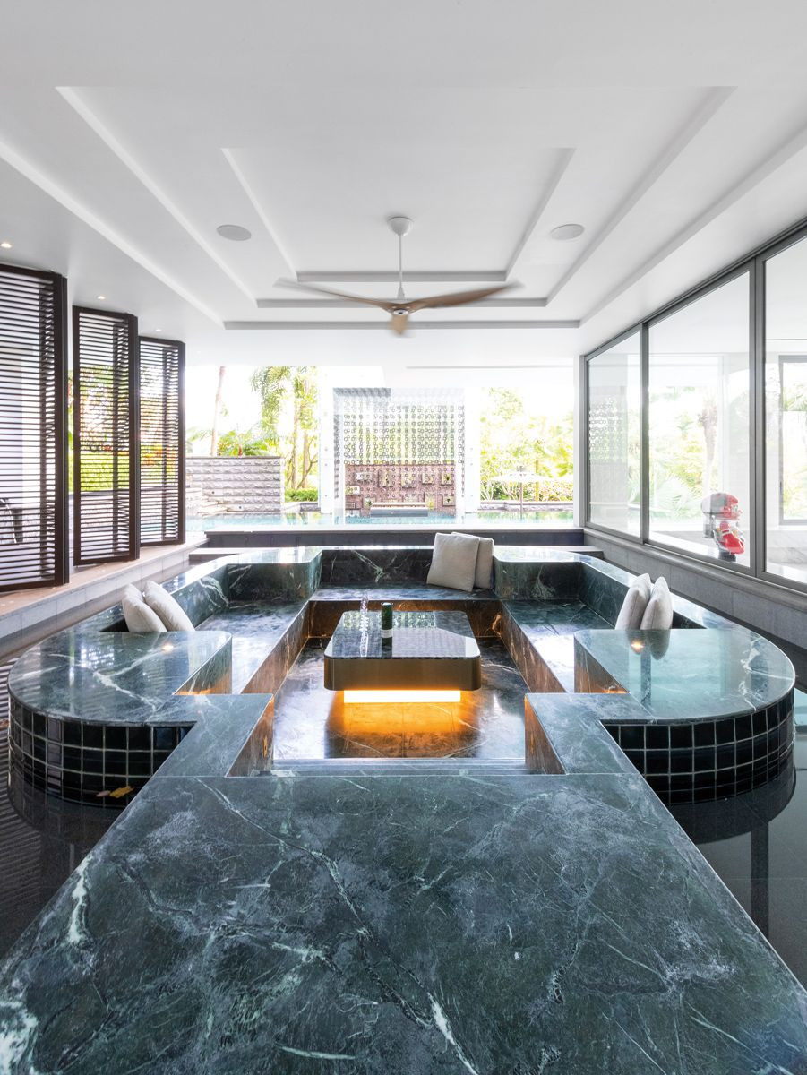 Finished in deep-green stone, this sunken seating area with a moat was formerly a jacuzzi that could fit 20 people, now reimagined to extend its functionality