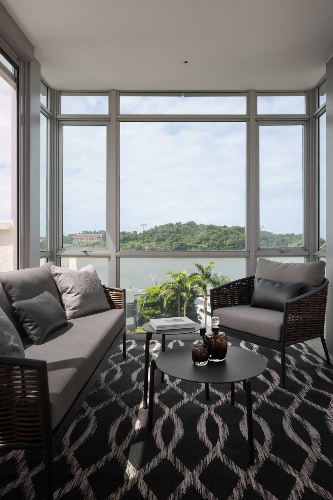 This section of the outdoor entertainment area is furnished with woven pieces and a patterned rug