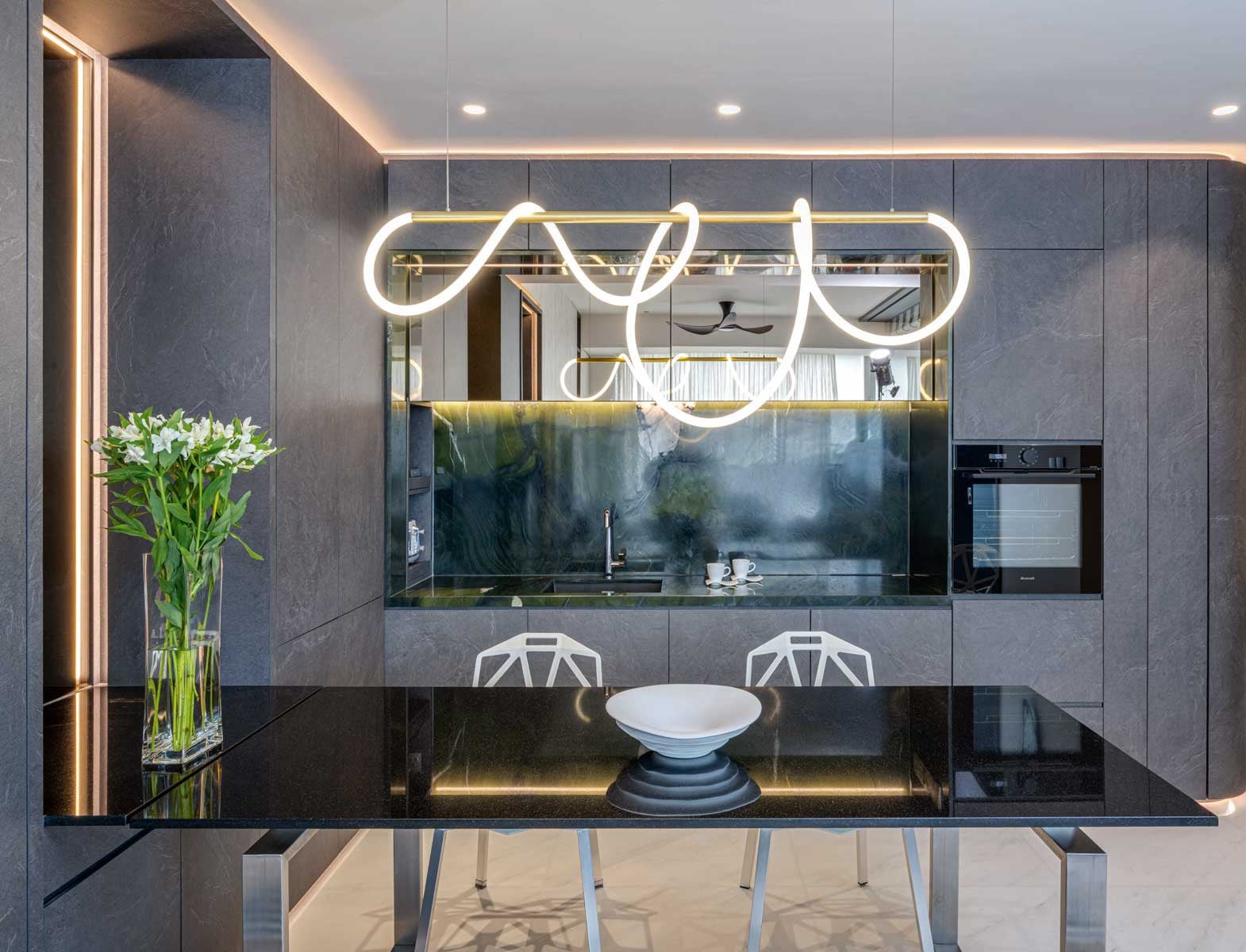 A sinuous lighting fixture softens the hard angles of the dining area and dry kitchen