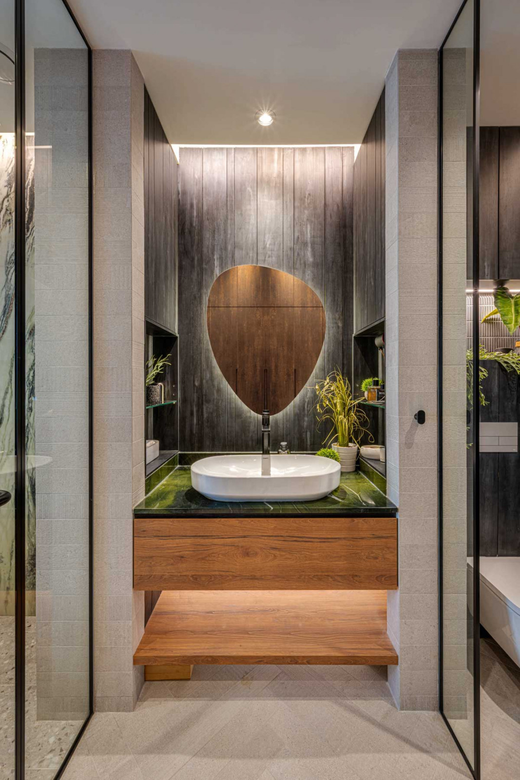 The asymmetrical mirror channels the ovoid form of the sink below