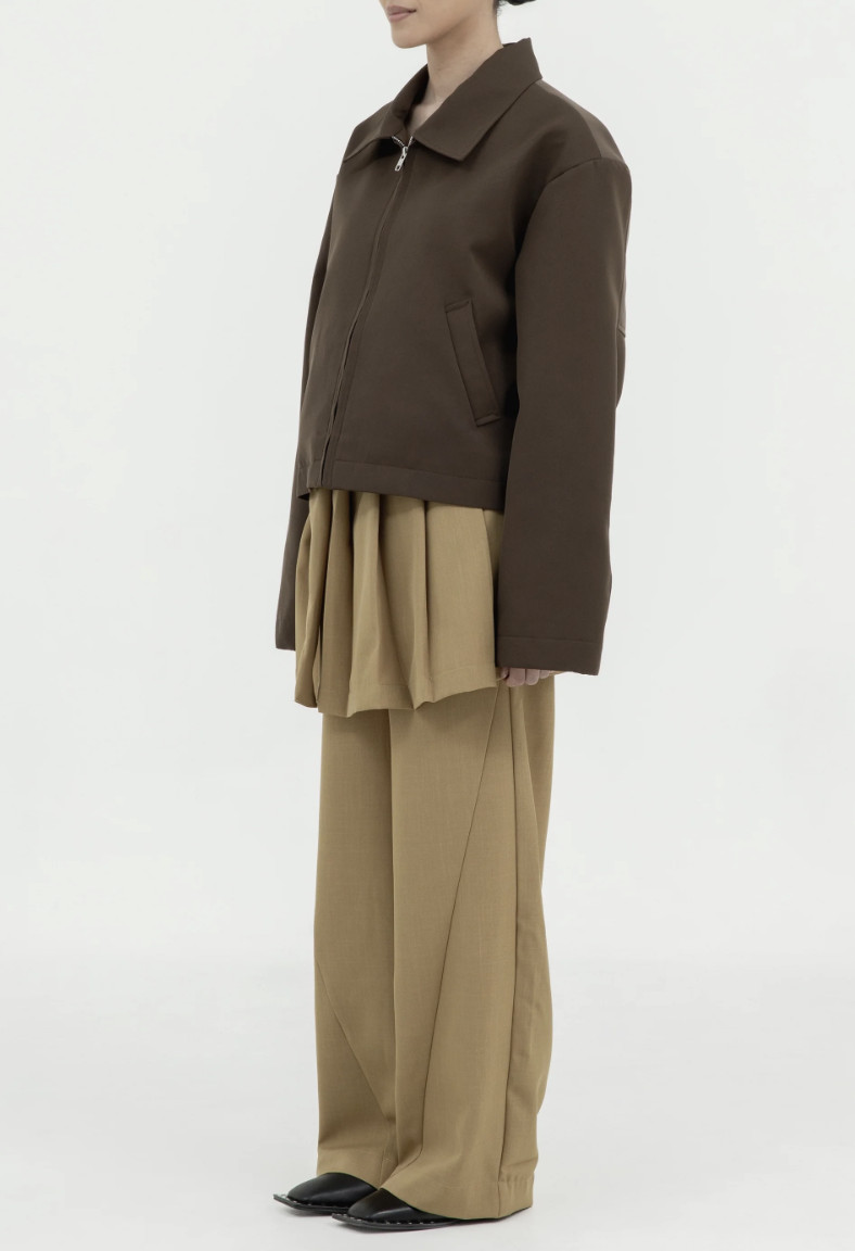Perpaduan jaket boxy berwarna cokelat gelap aksen lipit serta celana longgar milik Tanah Le Saé menghadirkan kesan earthy chic yang kontemporer (Foto: website  Tanah Le Saé)