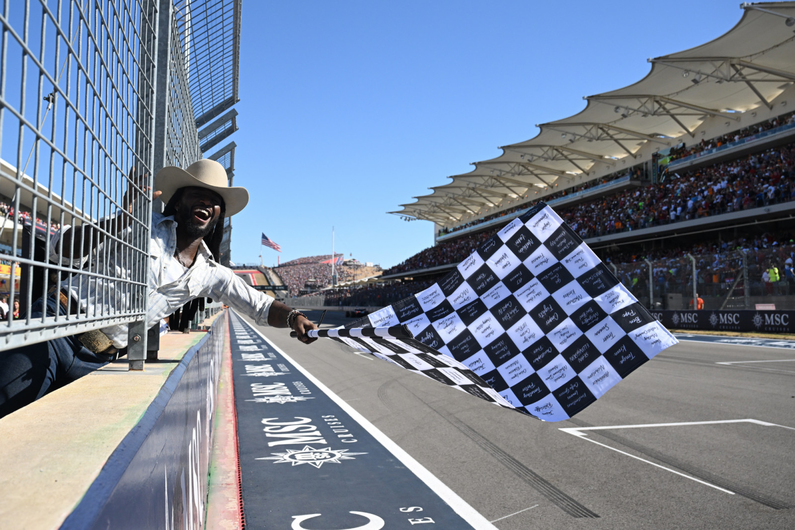 AUSTIN, TEXAS - OCTOBER 19: Shaboozey waves the chequered flag during the F1 Grand Prix of United States at Circuit of The Americas on October 19, 2025 in Austin, Texas. (Photo by Mark Sutton - Formula 1/Formula 1 via Getty Images)
