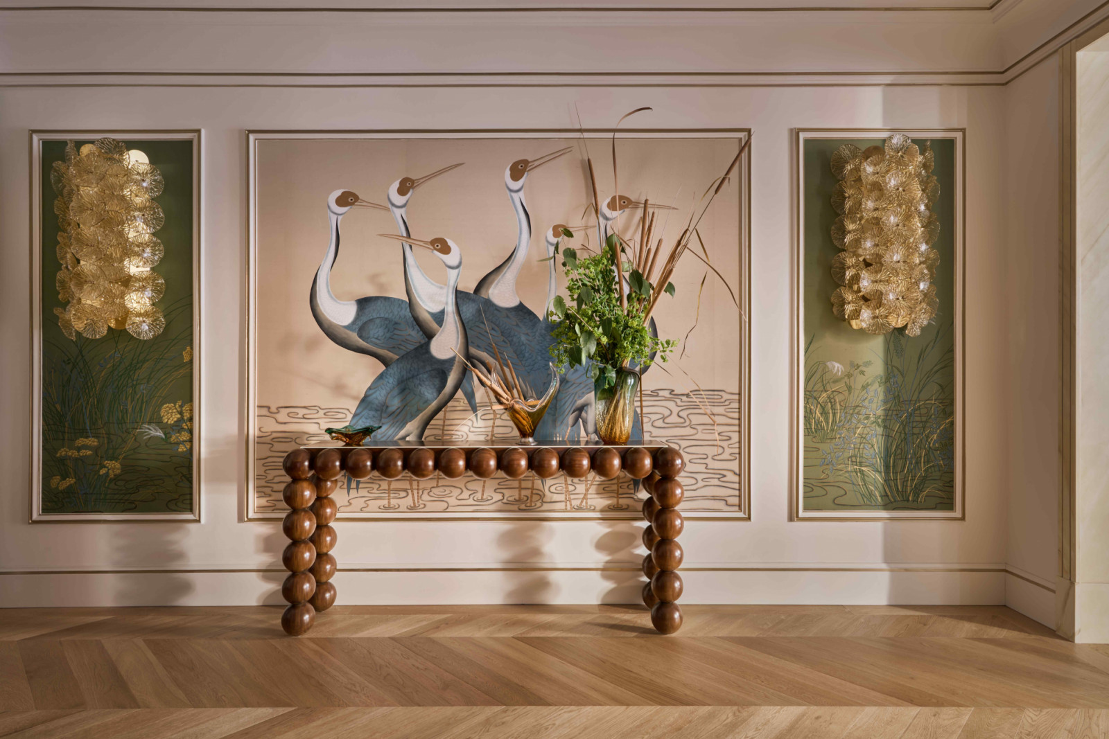 The large gallery entrance, featuring noble parquet flooring, luxurious de Gournay wallpapers, and shimmering antique sconces