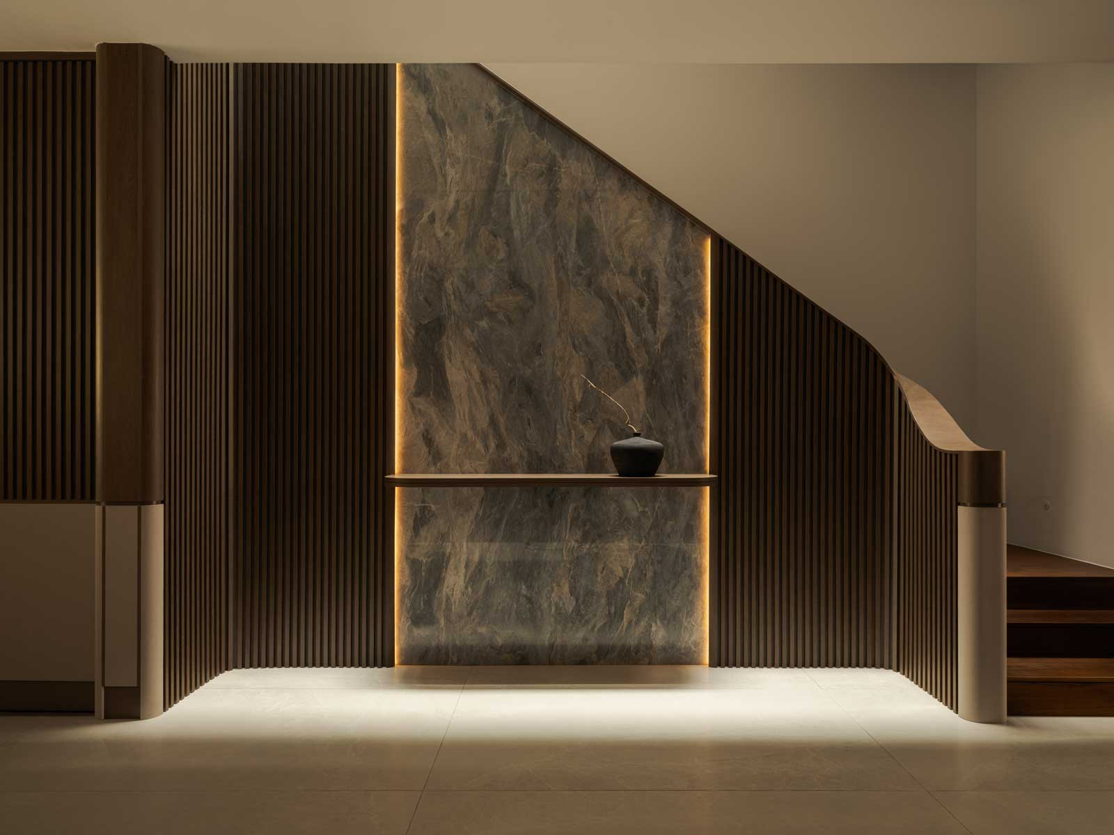 The stairwell doubles as a design feature with a softly lit, marble-clad feature wall