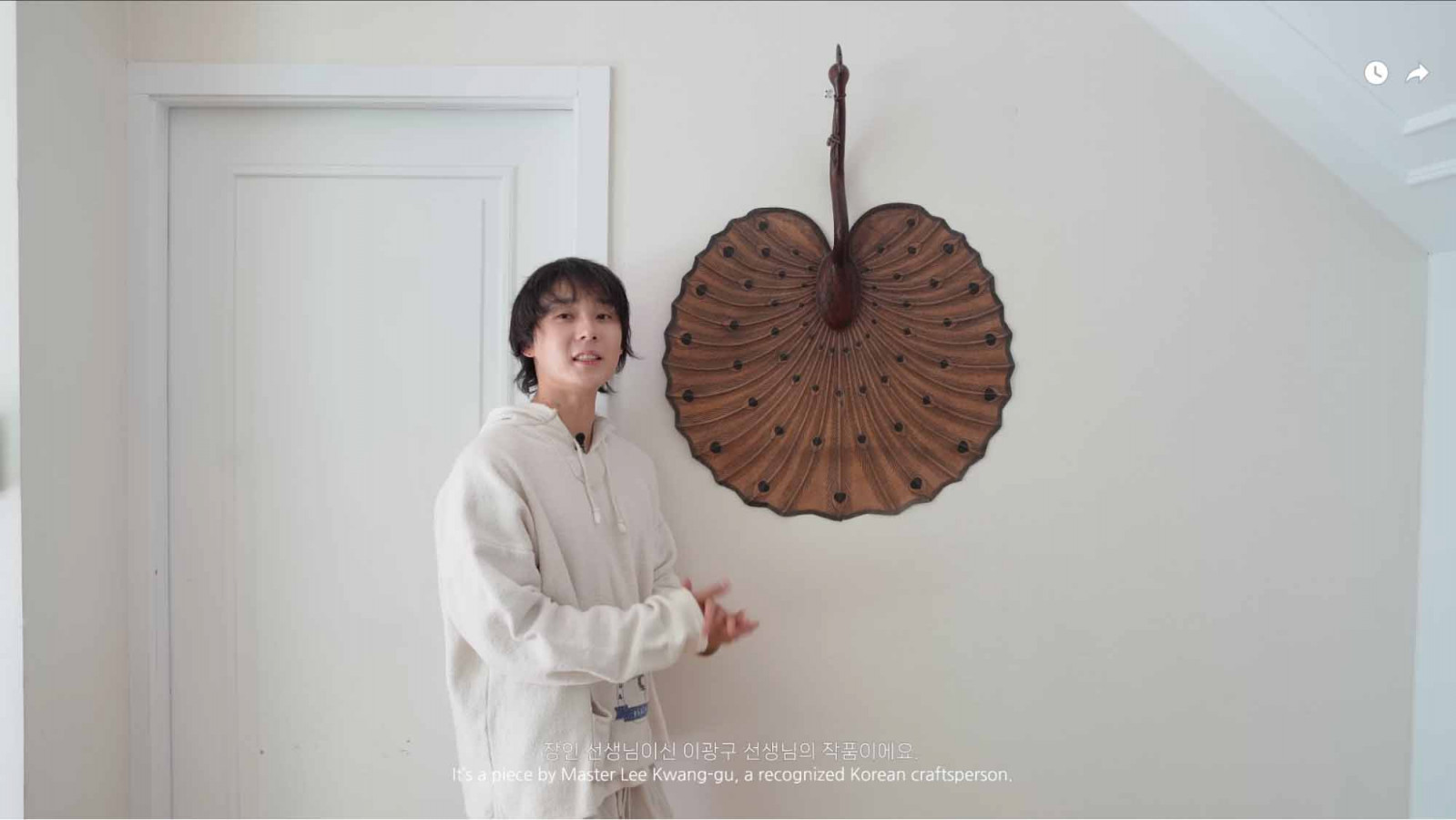 Dawn stands next to a peacock fan made by artisan Lee Kwang-gu (Photo: Youtube / DAWN)