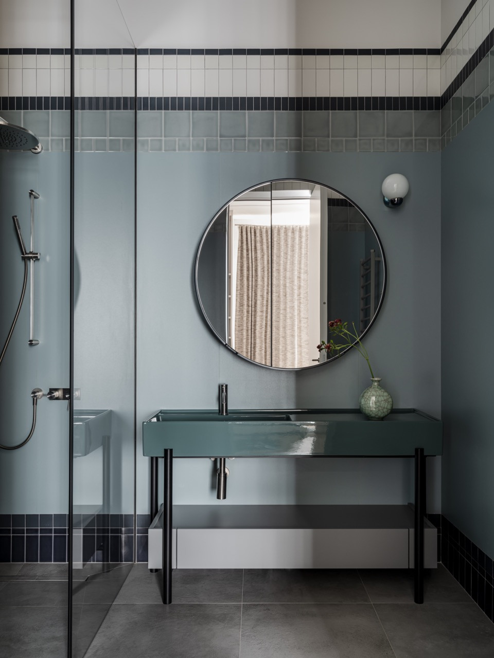 Full view of the son's bathroom, showing the shower area with a glass partition and a coordinated tile pattern that continues the horizontal colour bands