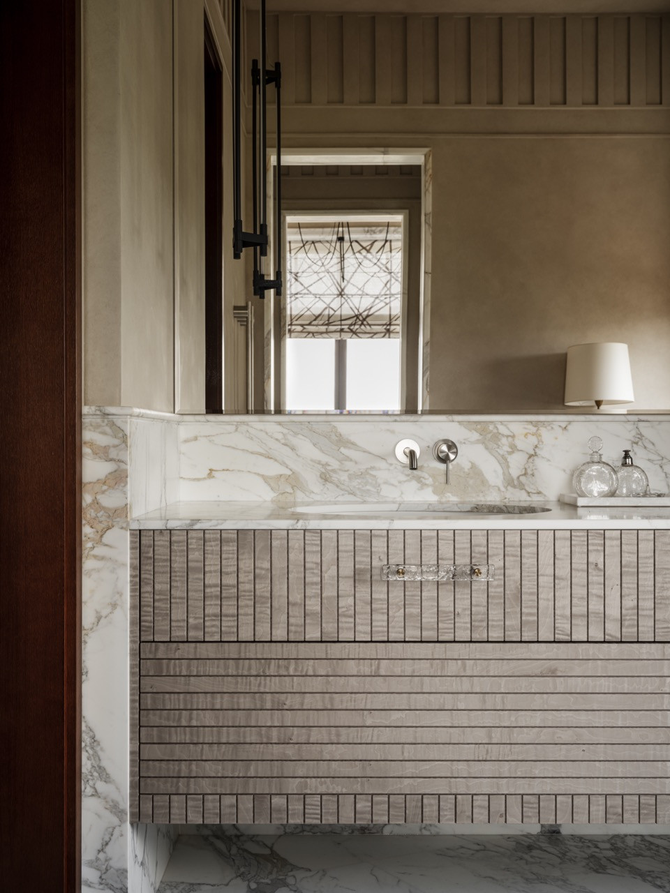 Master bathroom vanity area with custom-designed unit featuring sycamore veneer facades, textured glass handles by Soda Home Decor, and Calacatta Vagli marble backsplash
