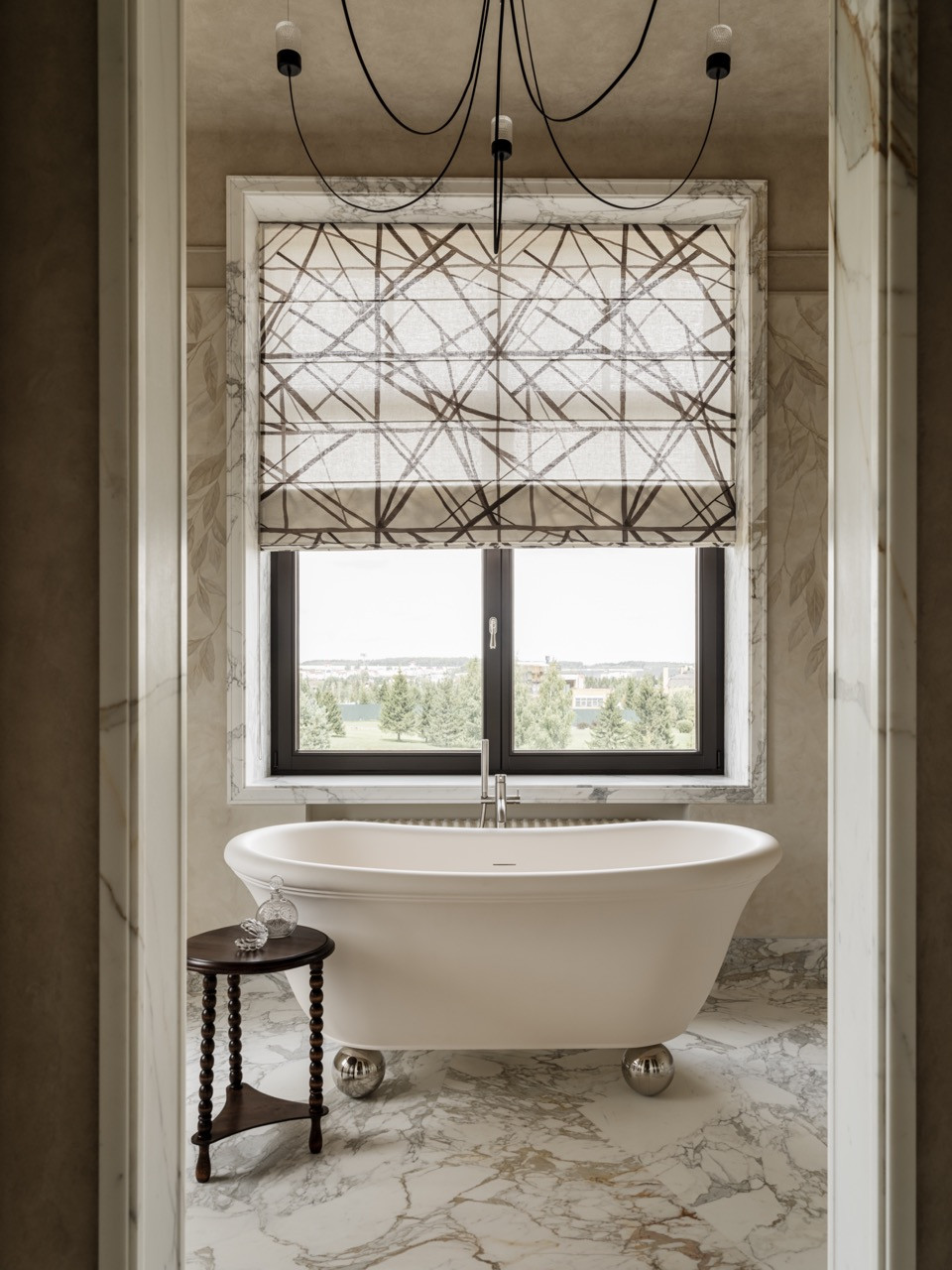 View through doorway to master bathroom showing Devon & Devon bathtub framed by window with geometric patterned roman shade and pendant lighting by Moooi