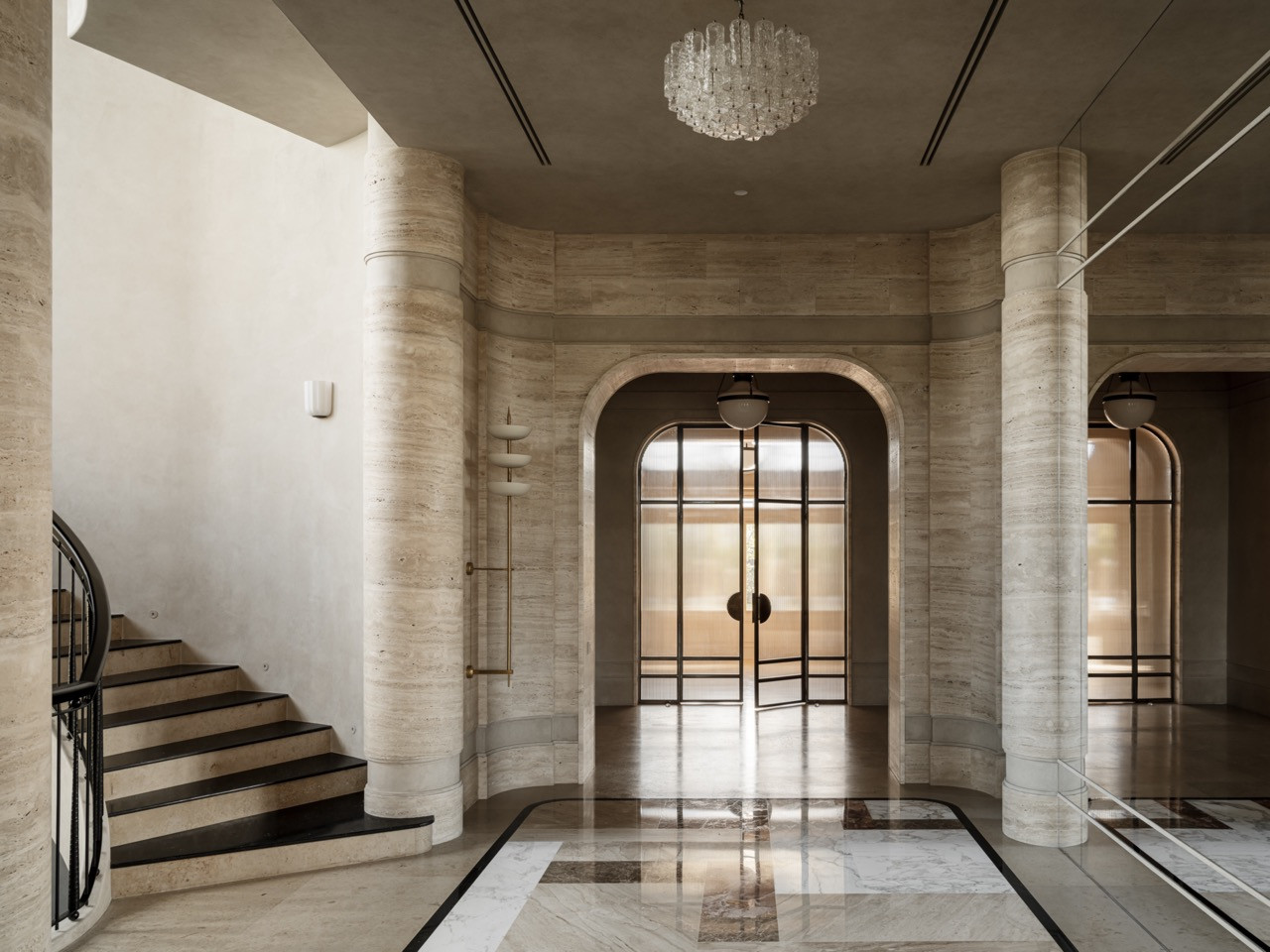 The grand staircase hall has walls entirely clad in travertine, featuring monumental curved architecture