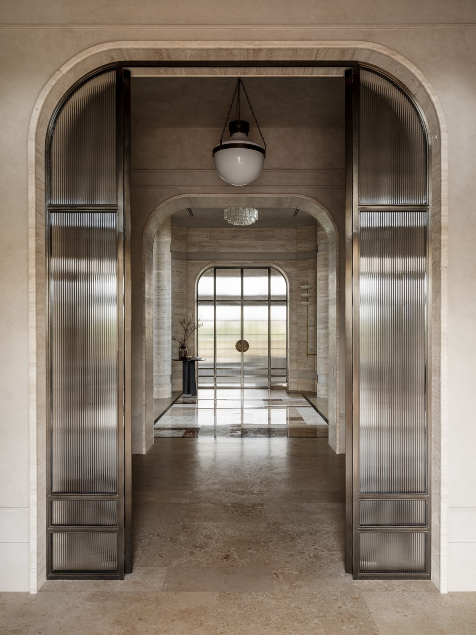 Layered view through arched glass doorways from the entrance to the staircase hall