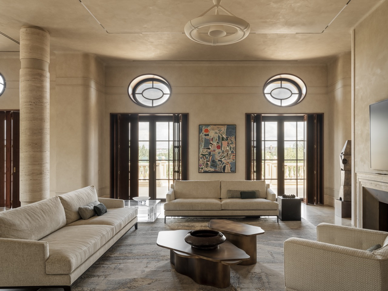 Living room with symmetrical French doors opening to the terrace and Poliform sofas arranged around custom brass coffee tables