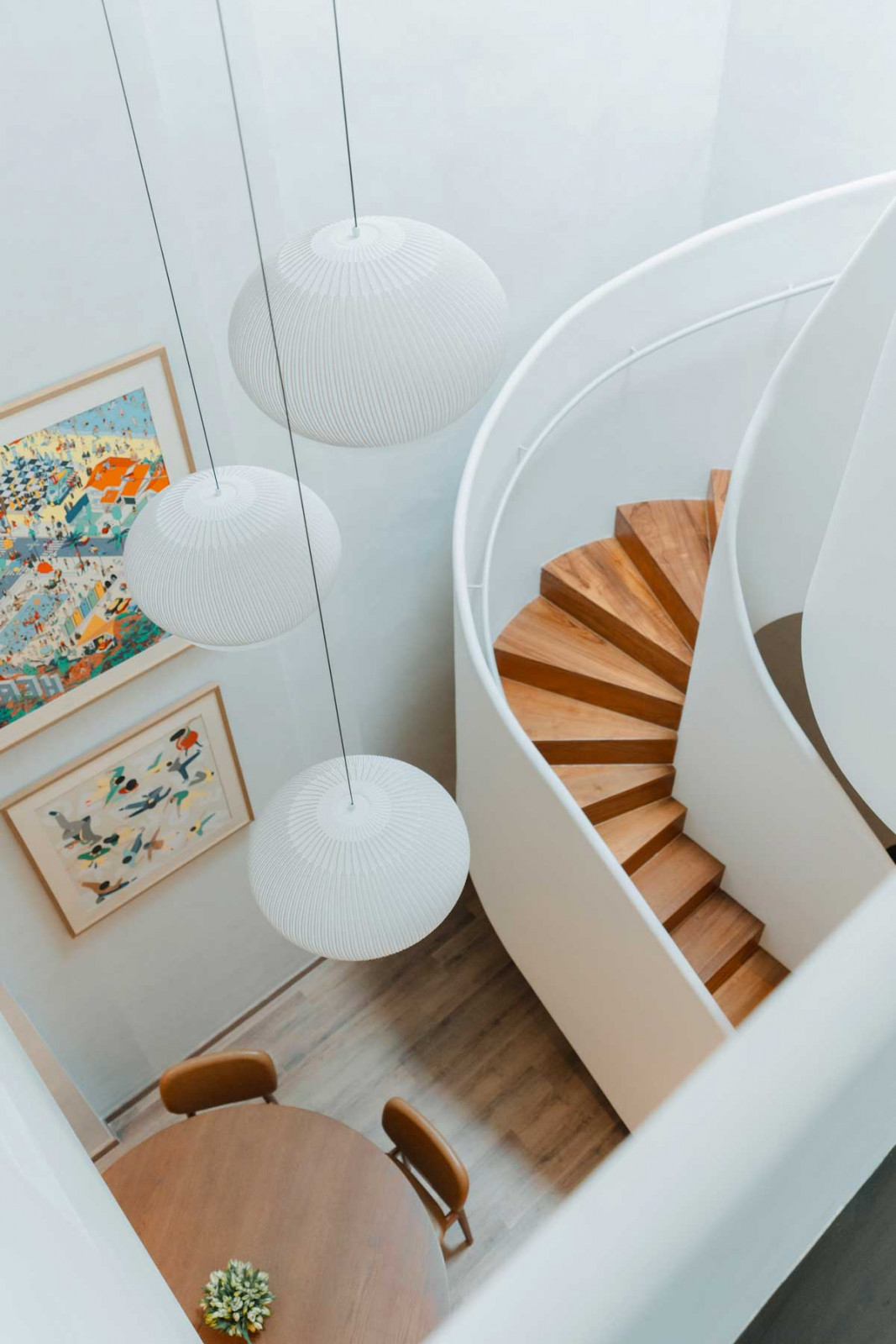 A winding staircase brings drama to the double-height space while framed Hermès scarves introduce vibrant colour