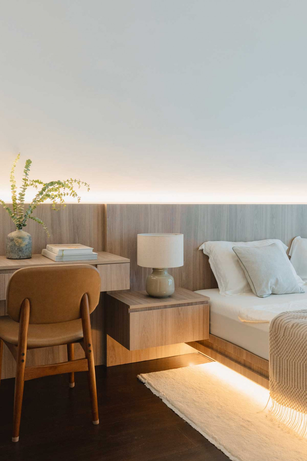 The headboard carpentry extends seamlessly into the bedside table and study desk
