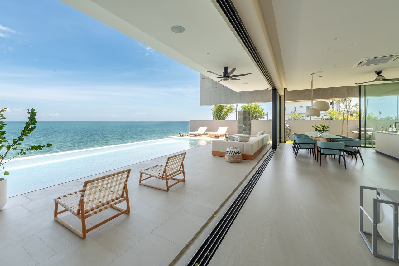 Low-slung beach chairs and modular seating create a relaxed atmosphere that flows seamlessly to the infinity pool and ocean beyond