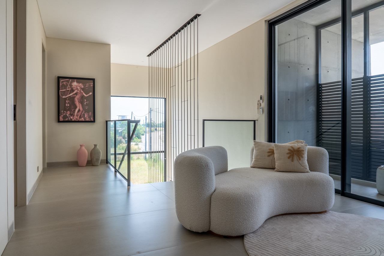 The upper-level retreat features a sculptural curved sofa and curated artwork
