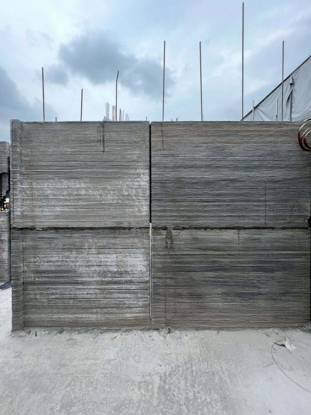 A full-height panel wall during construction reveals the striated layers and alignment precision of QR3D’s additive printing method, before integration with other materials