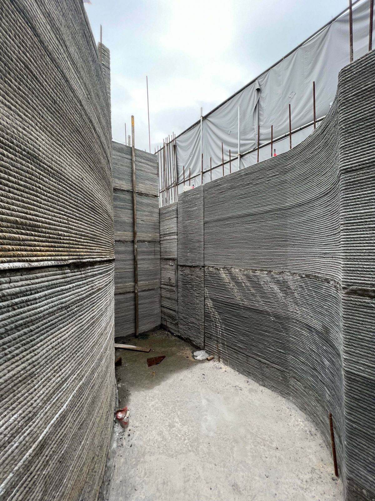 Captured during construction, the 3D-printed concrete walls reveal their layered texture and curvature before finishing—demonstrating the expressive possibilities of the QR3D process