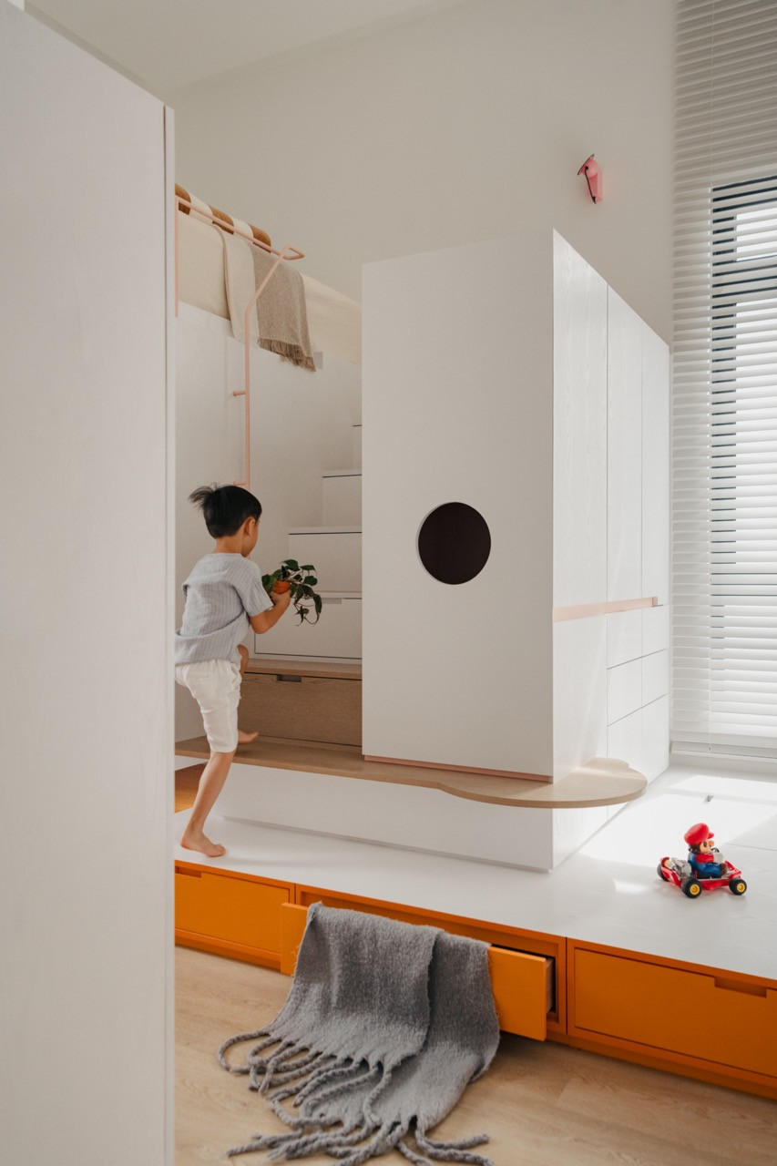 One of the children’s rooms showcases vibrant orange built-in storage with flexible raised platforms providing both seating and play areas