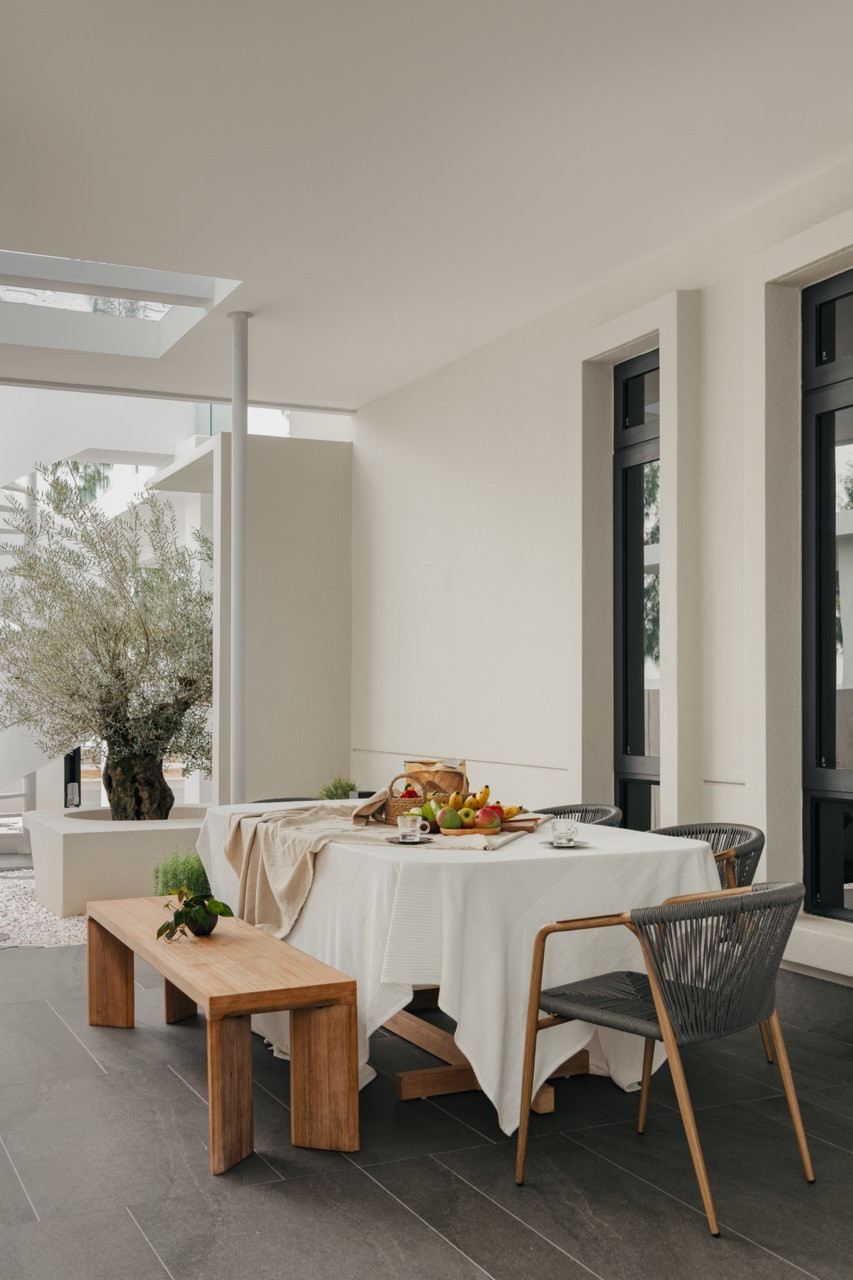An outdoor dining area featuring sculptural wooden benches exemplifies the home’s connection to nature