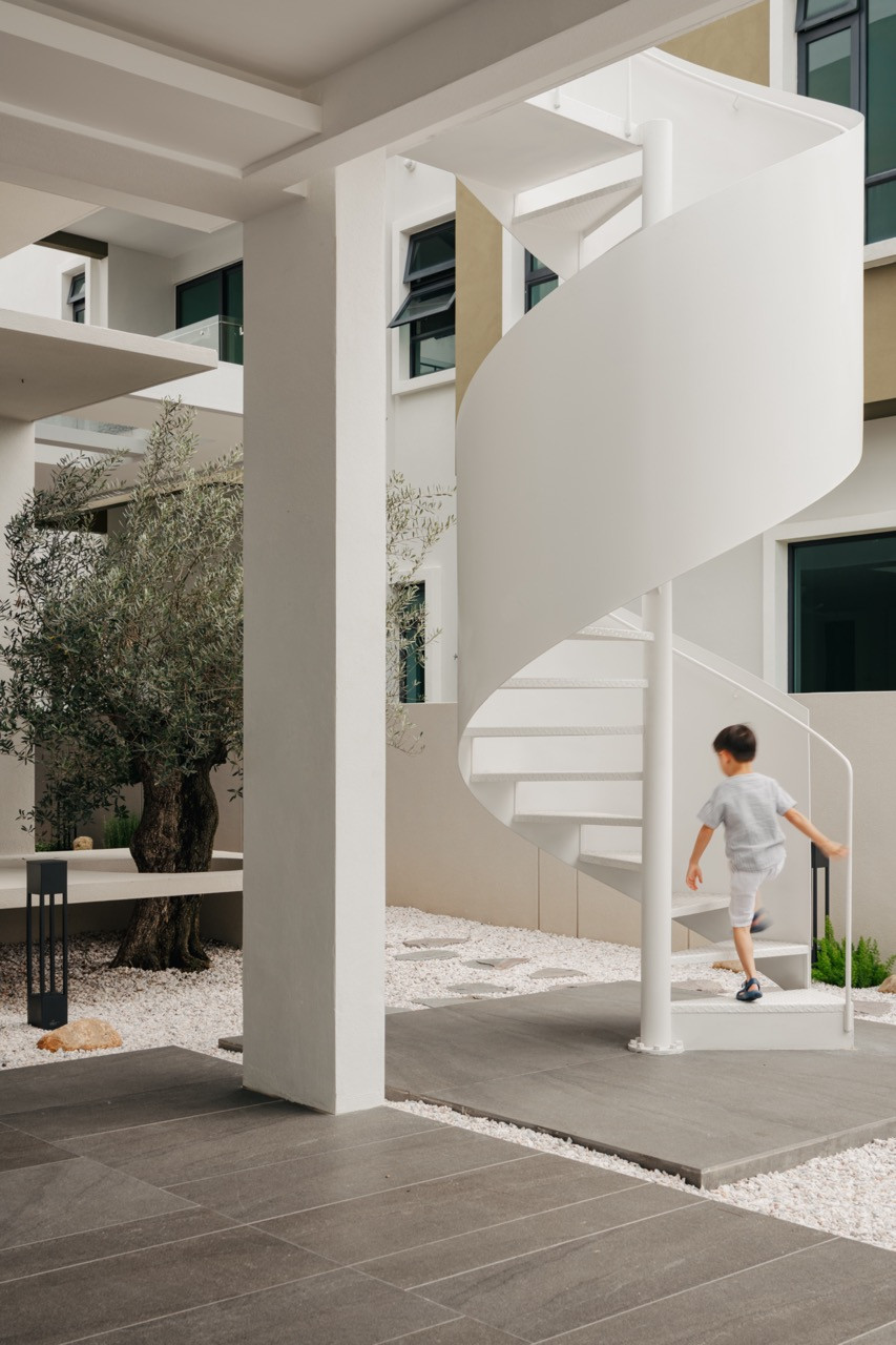The outdoor spiral staircase serves as a pure white sculptural focal point, contrasting beautifully with the clean modern facade