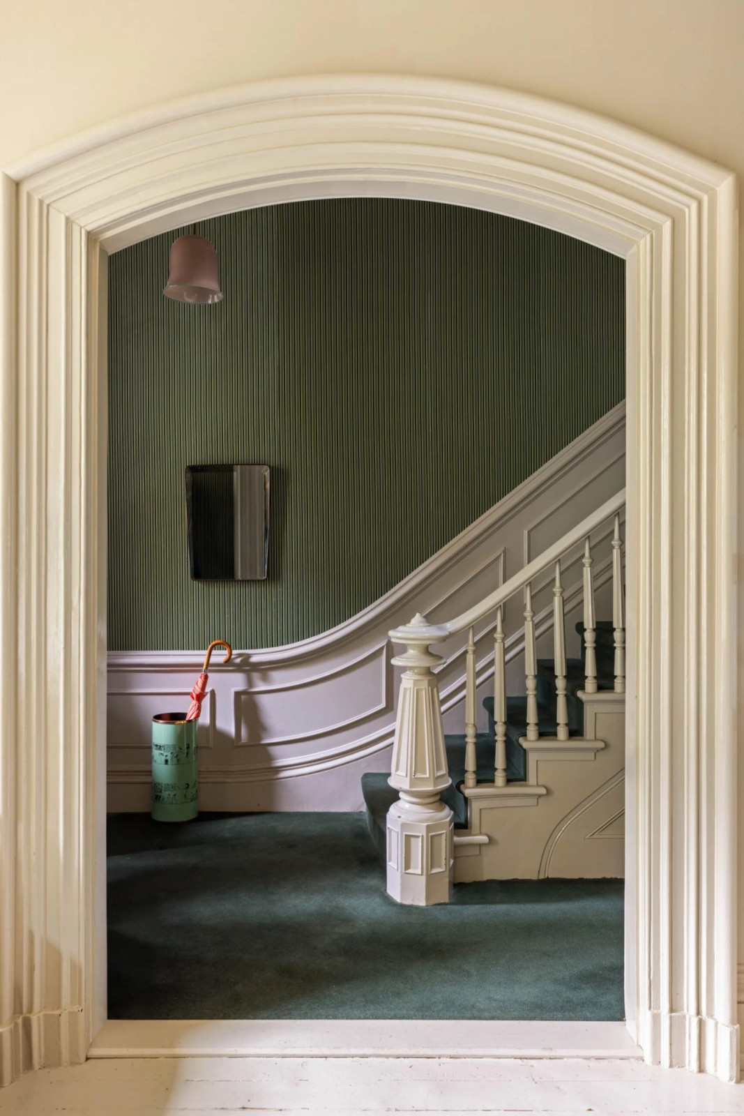 Original wainscoting and detailed mouldings line the stairwell, with green-and-white striped wallpaper above (Photo: The Gambino Group)