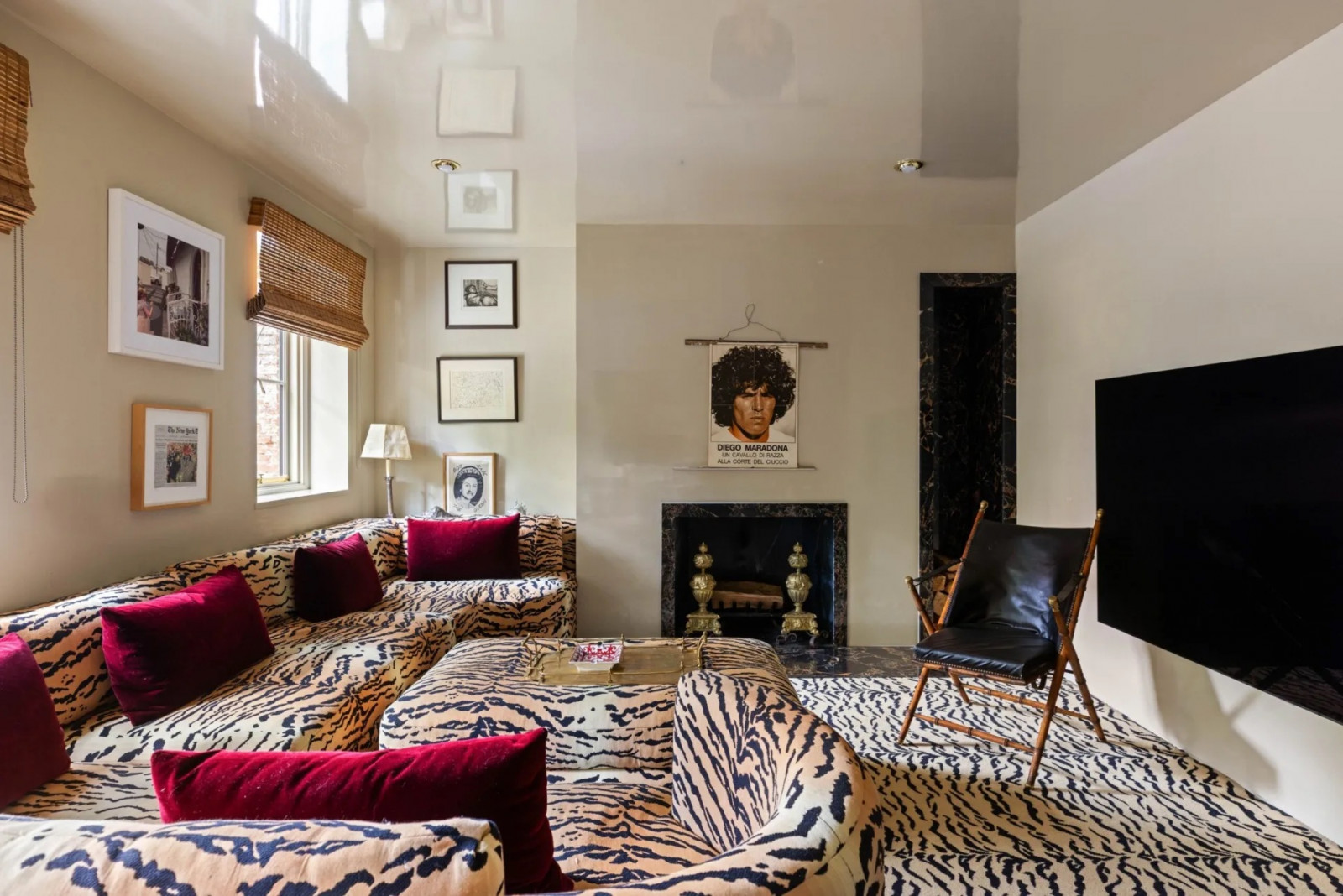 The media room features wall-to-wall tiger-print carpet that extends onto the sofa and ottoman, with magenta velvet cushions (Photo: The Gambino Group)