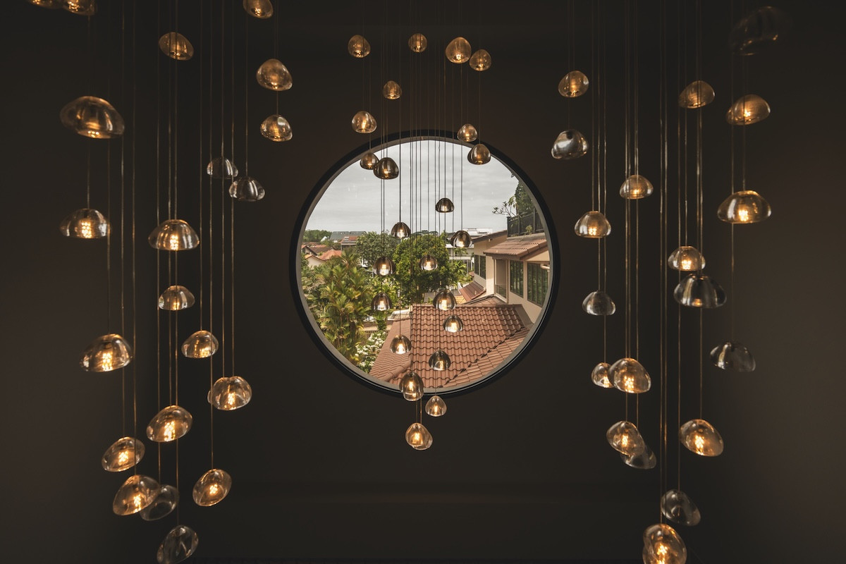 The neighbourhood vista as glimpsed through a porthole window, with pendant-light clusters in the foreground