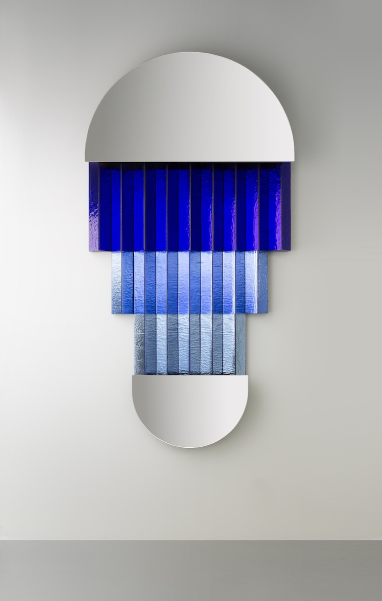 A mirror distinguished by a three-tiered cobalt blue finish on its metal frame