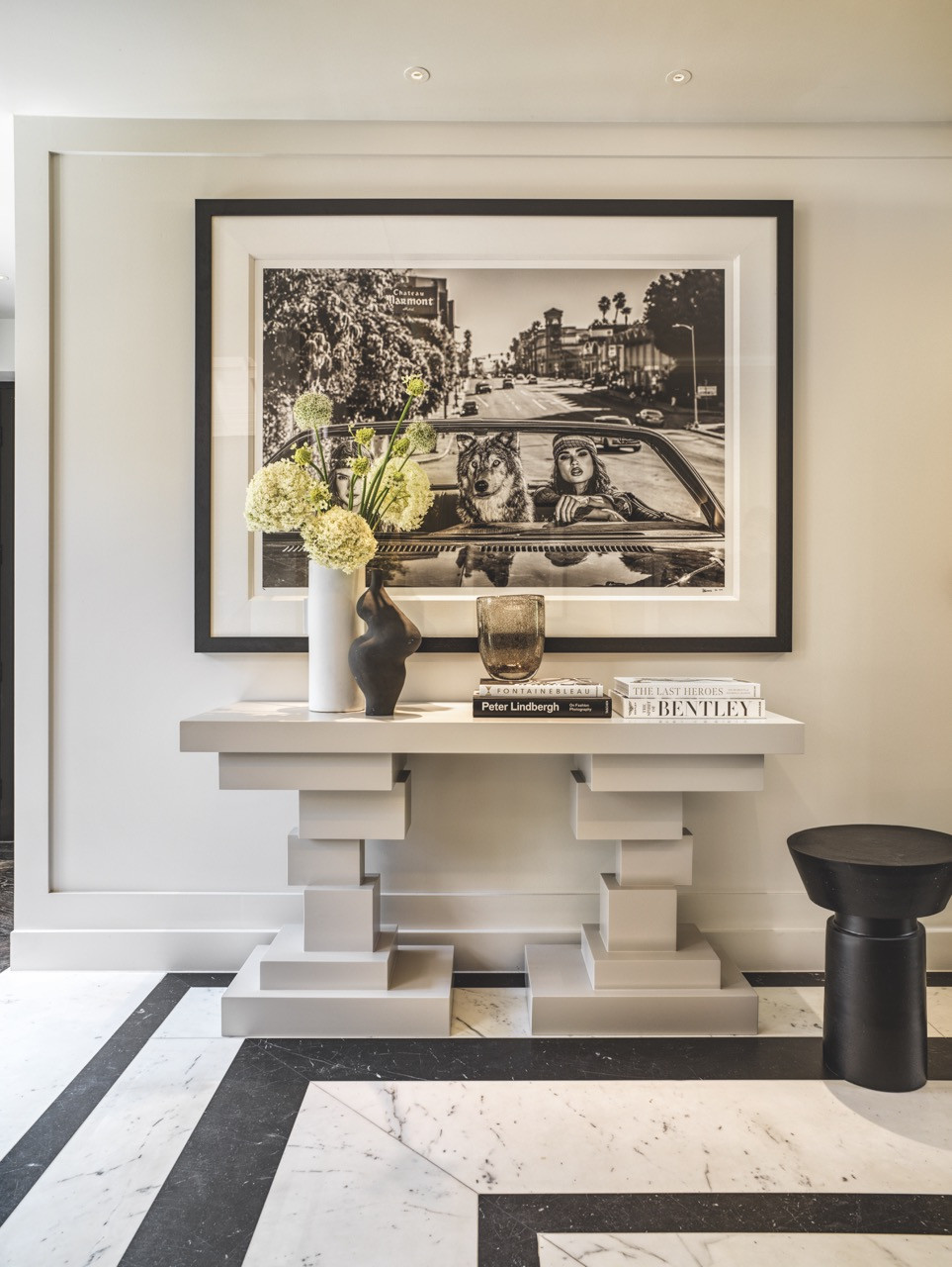 A bespoke console takes centre stage at the entrance, where geometric marble flooring contrasts against the warm lighting