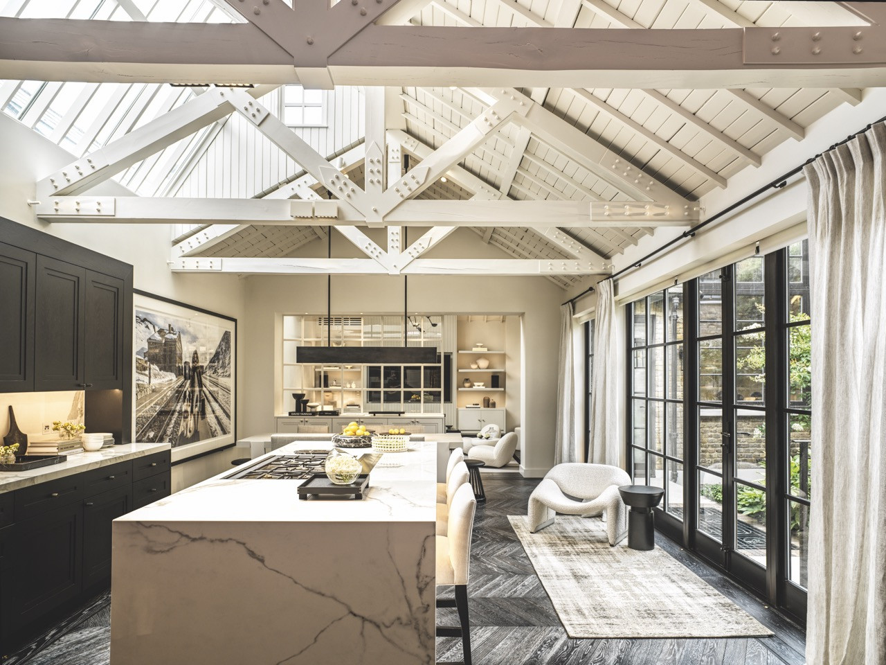 The kitchen showcases exposed white-painted beams against dark cabinetry