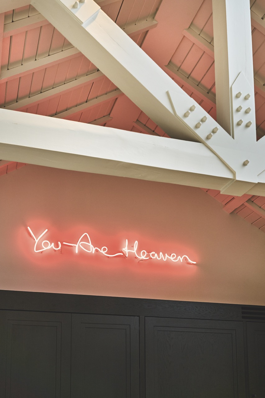 At the entrance, pale green paint brightens the beams, offset by a pink neon artwork