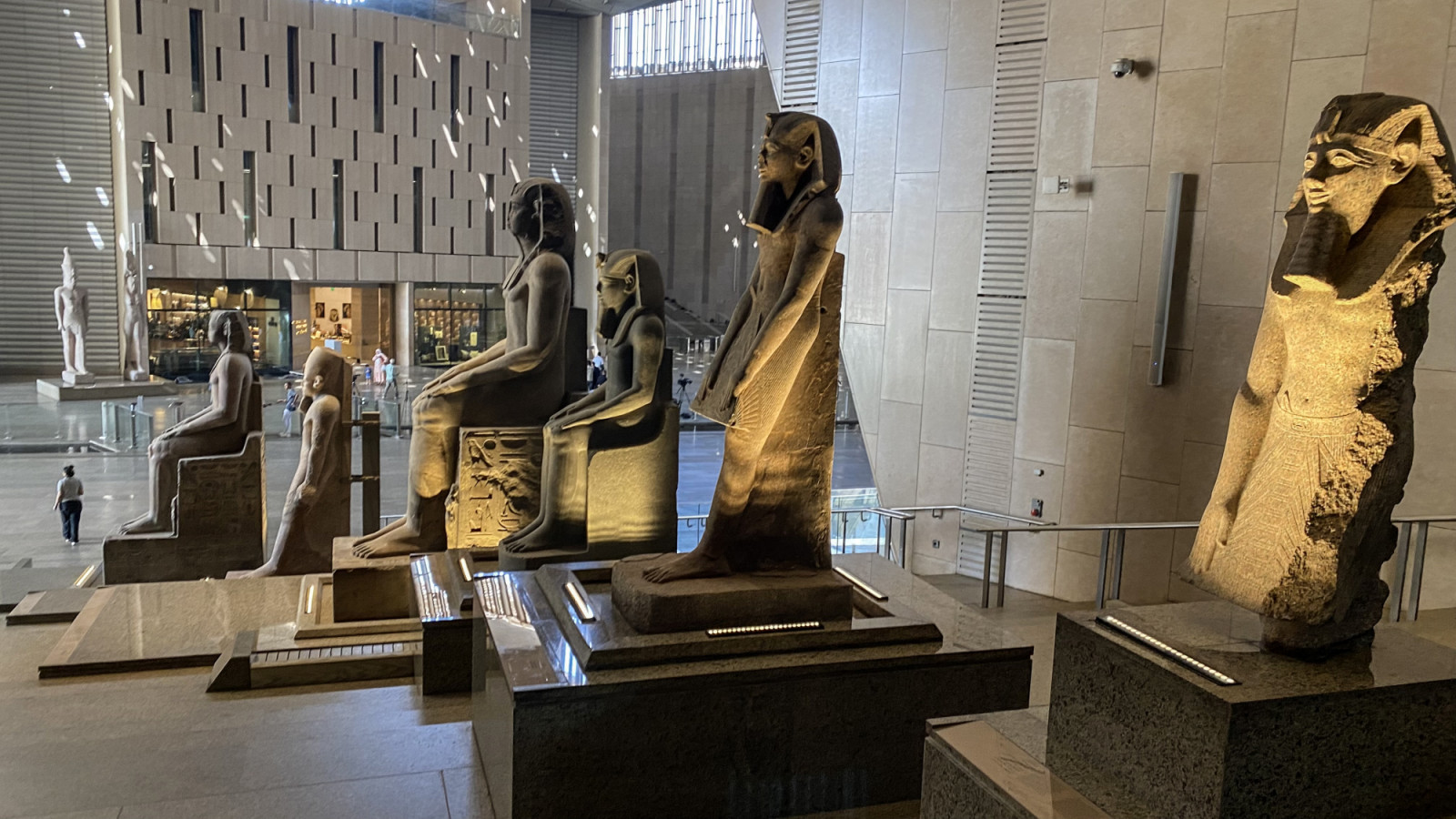 GIZA, EGYPT - OCTOBER 15: A view of sunlight pouring into the Grand Egyptian Museum's main hall, illuminating a row of colossal statues of pharaohs seated in regal poses at the Great Egyptian Museum, the world's "largest museum exhibiting the artifacts of a single country", includes 12 exhibition halls covering the entire ancient history of Egypt on October 15, 2024 in Giza, Egypt. Built in the city of Giza, where the Egyptian pyramids are located, the museum houses thousands of artifacts starting from the