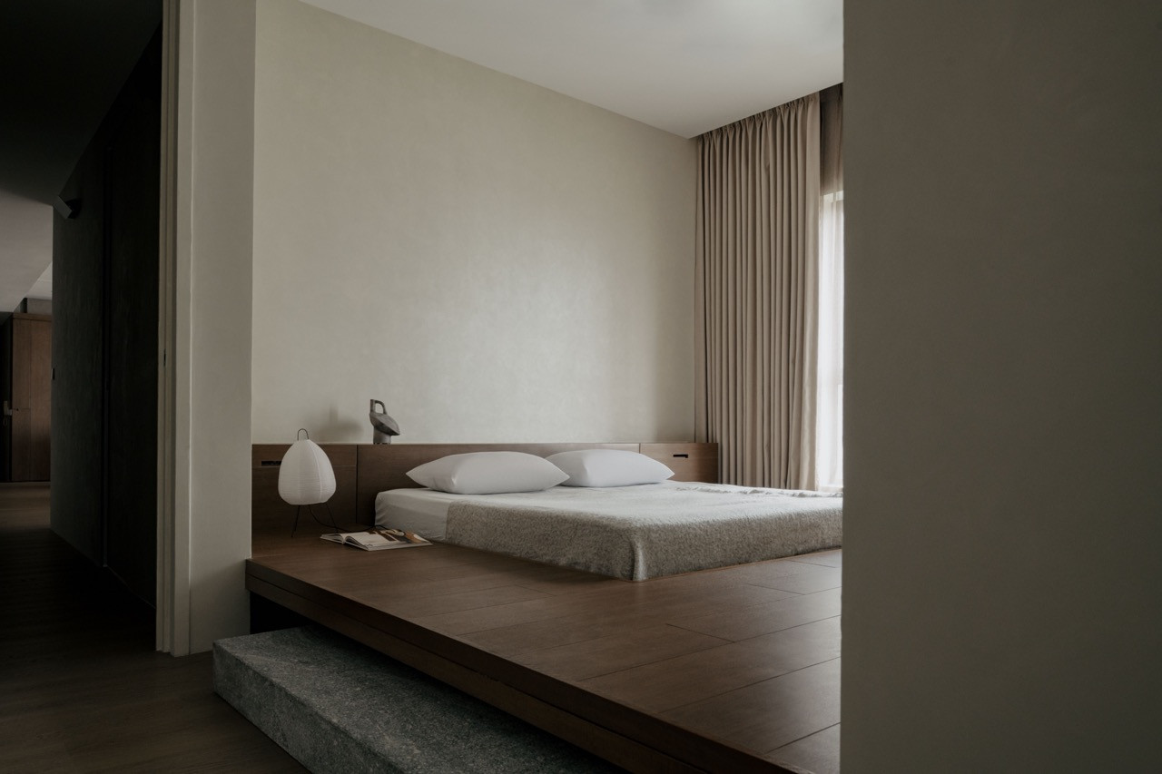 The platform bed sits elevated on a granite base, viewed from the shadowy entrance corridor