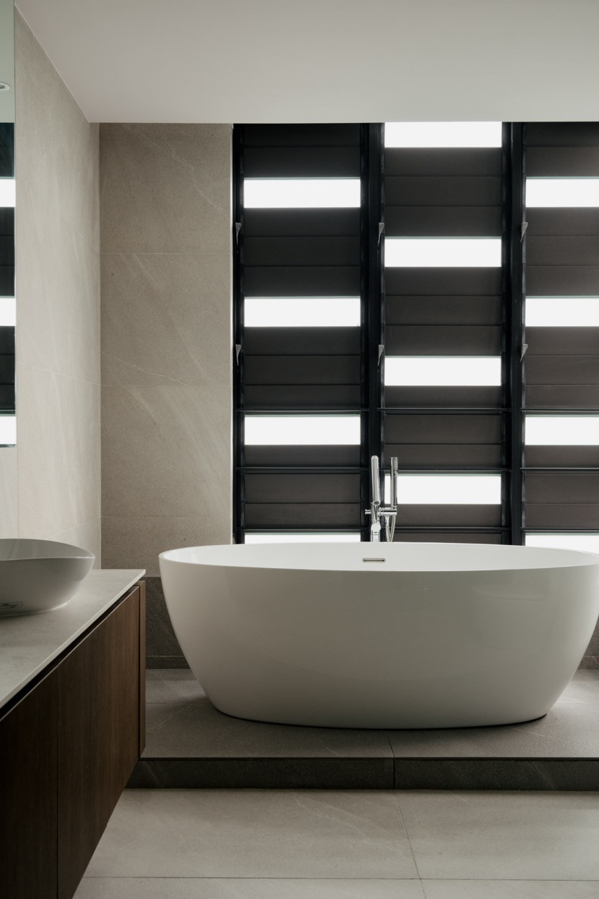 The bathroom features a freestanding tub set against textured cement walls, with dark external shutters controlling natural light
