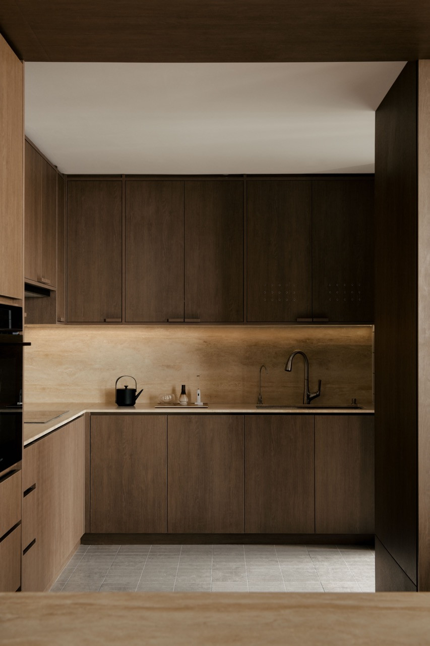 The kitchen features oak cabinetry with under-cabinet lighting, demonstrating the warm wood tones in Wuuu Studio's material palette