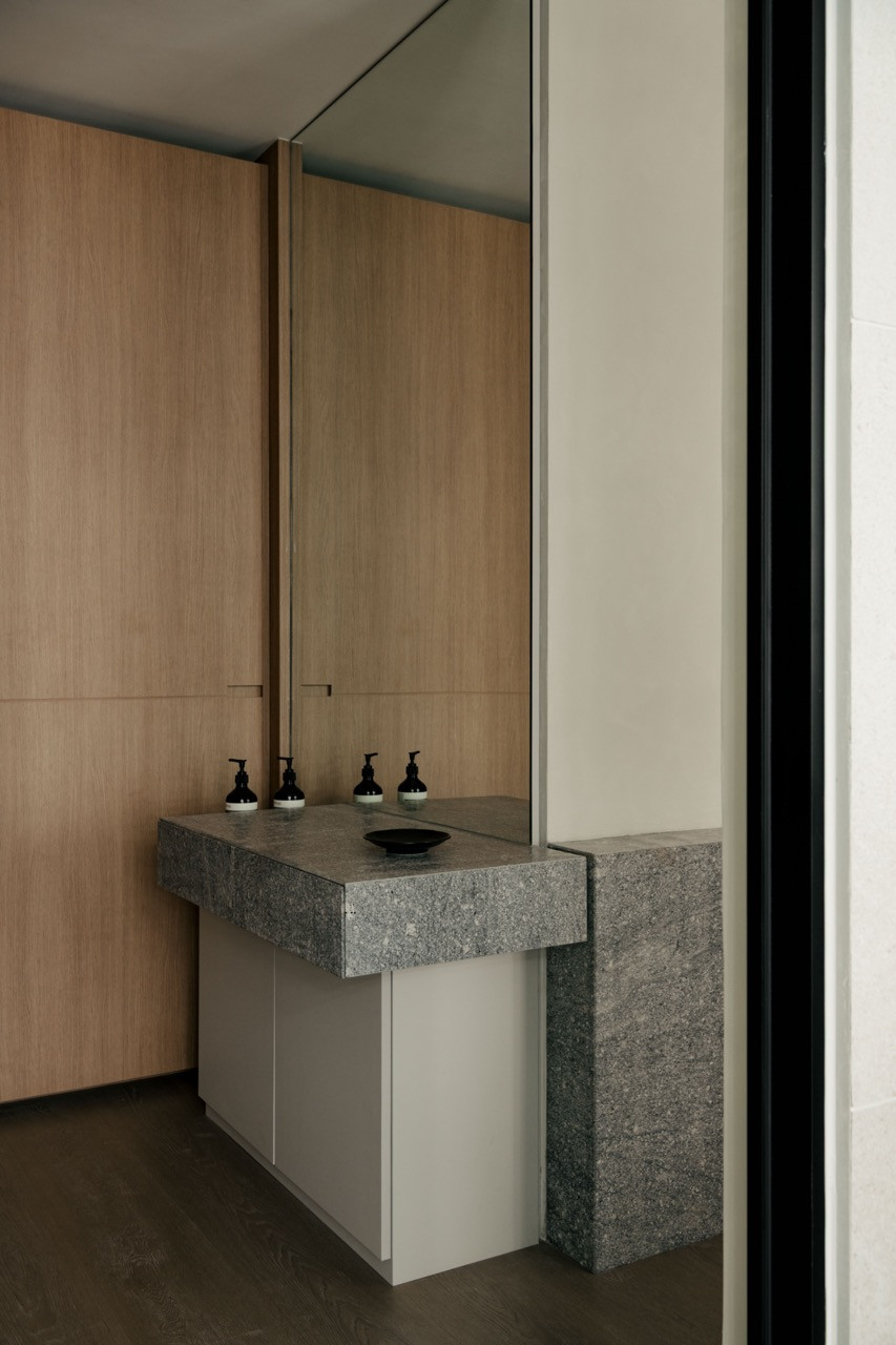 A granite vanity counter extends from the wall in the powder room, backed by floor-to-ceiling oak storage