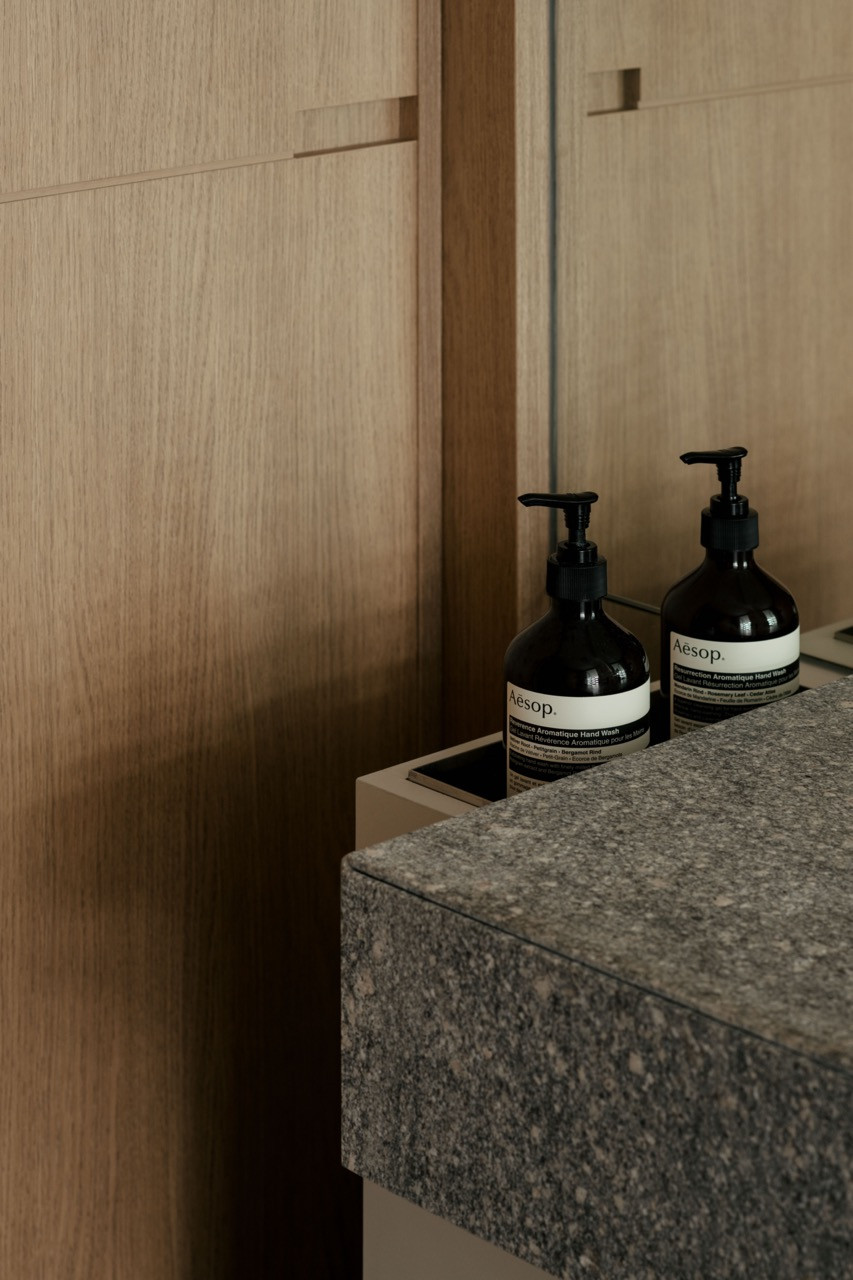 Oak cabinetry and granite surfaces in the bathroom reflect the apartment's philosophy of material duality