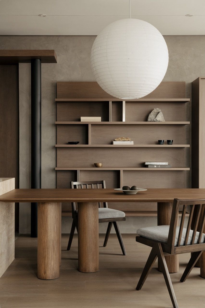 Oak furniture and shelving create layered zones in the dining area, with cement walls providing neutral backgrounds