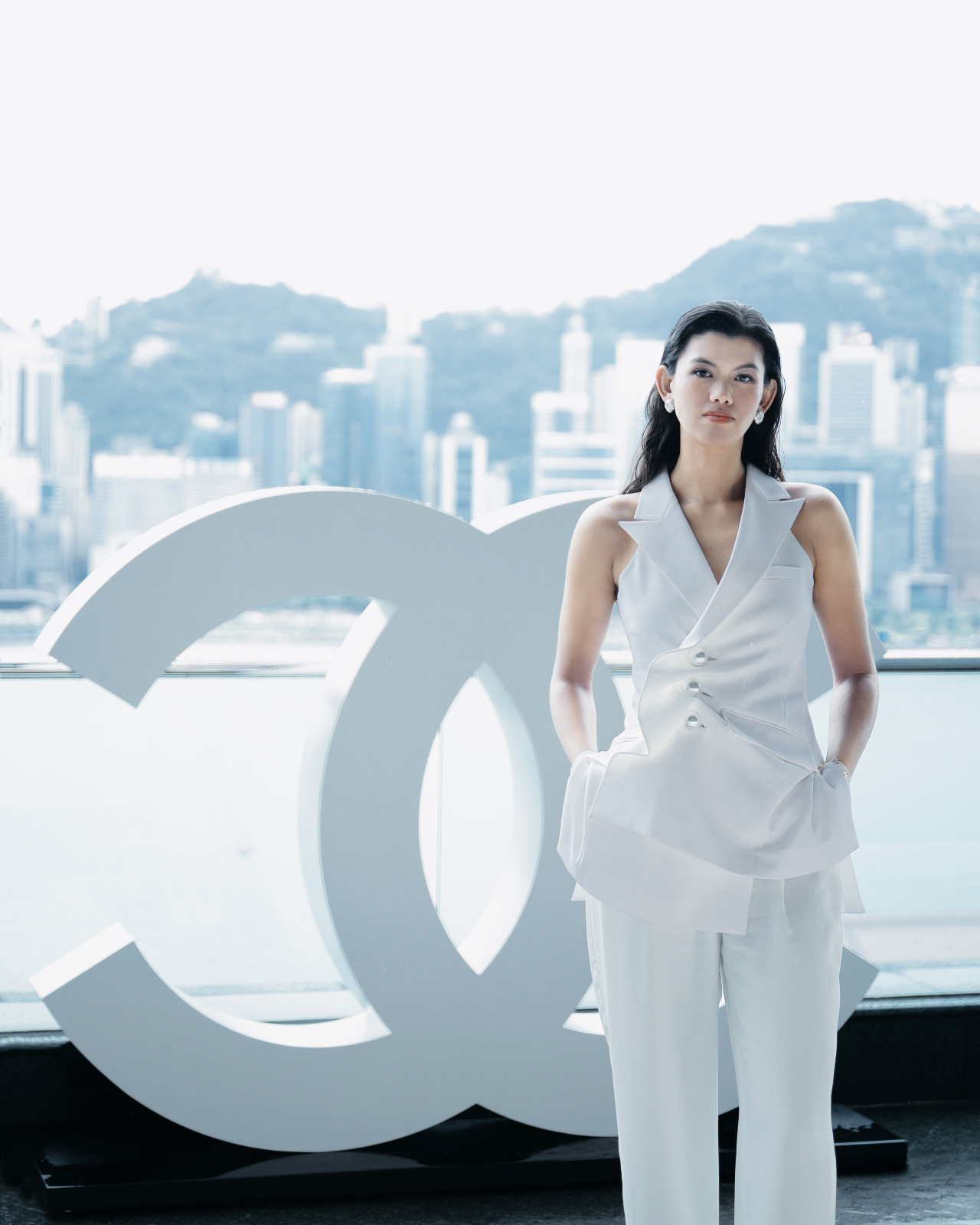 Martinesi stands next to a Chanel logo statue on a balcony at The Peninsula Hong Kong, overlooking Victoria Harbour (Photo: Tatler Hong Kong)