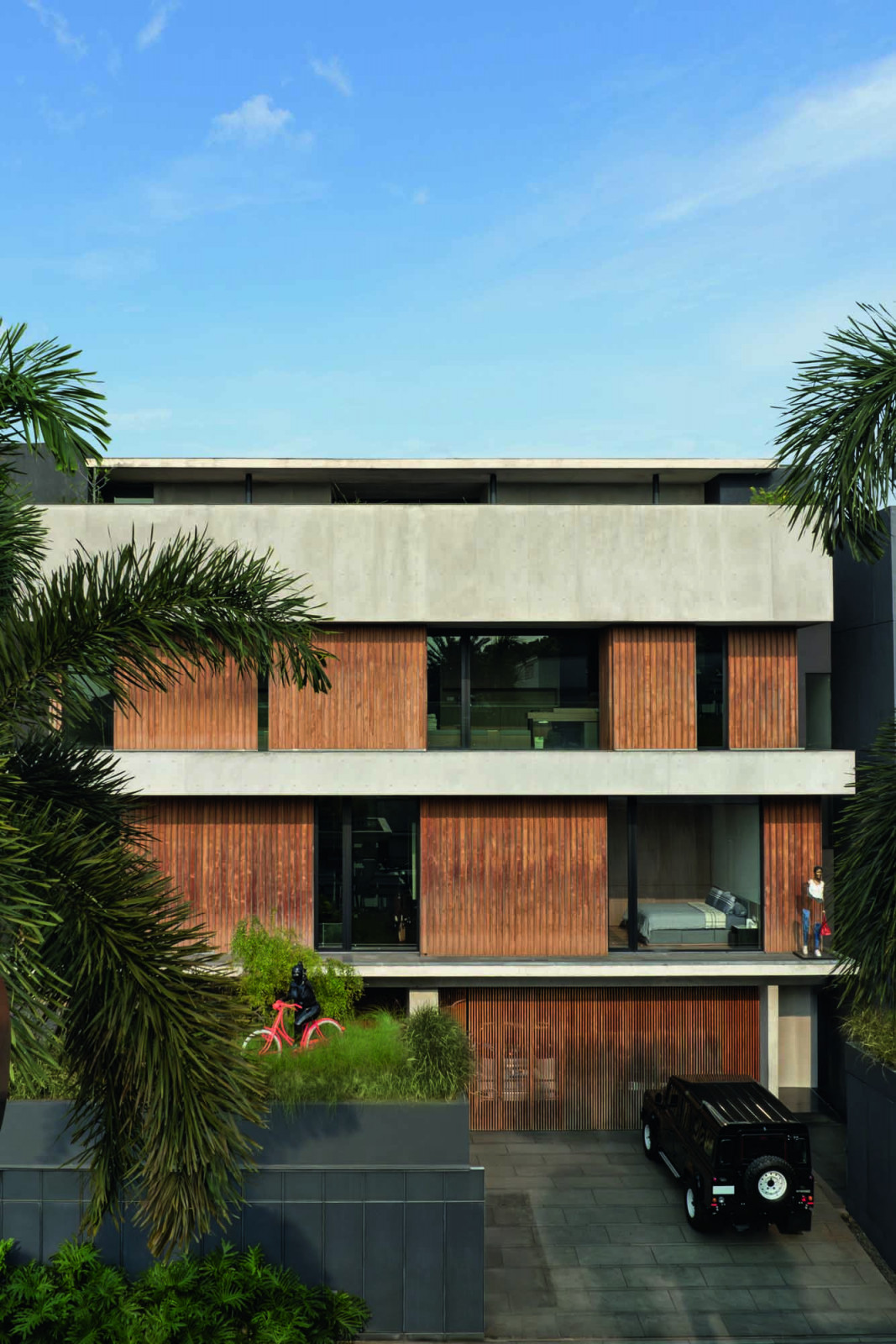 The exterior of the Pondok Indah house also features sculptures playing peekaboo among the grass planters and the timber-and-concrete facade