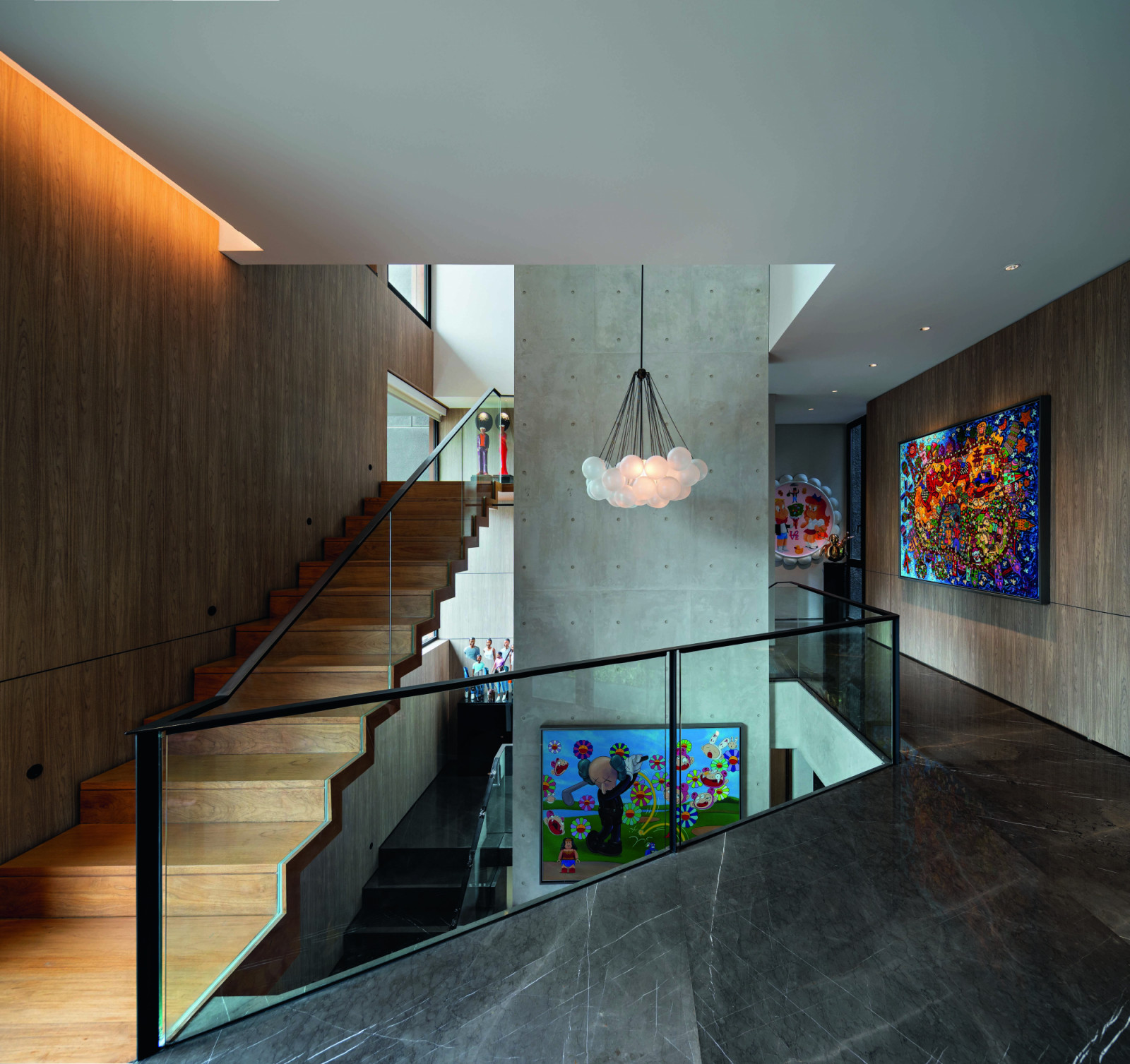 A view of the vertical “art gallery” from the second floor shows how the muted material palette provides the perfect backdrop for the art pieces