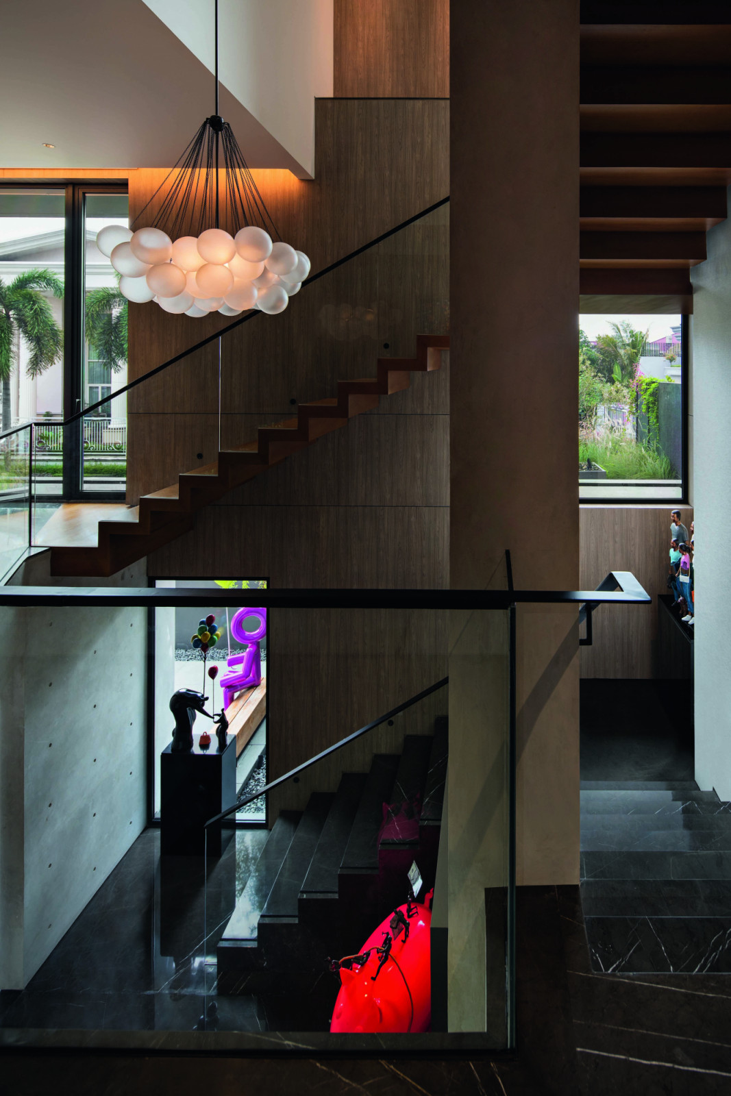 The stairwell is envisioned as an art gallery, dotted with openings and pieces to admire along the vertical journey through the home
