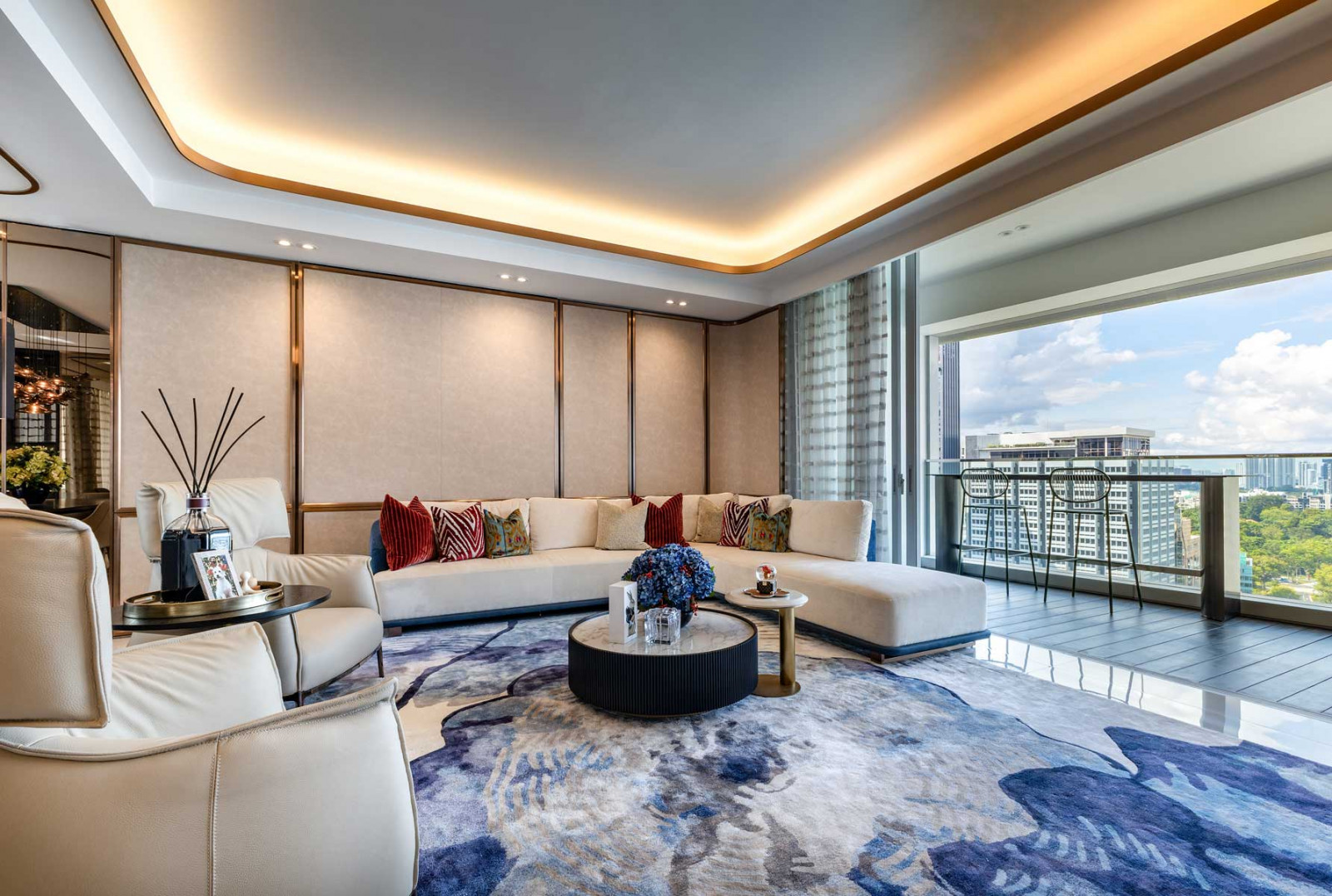 The expansive living area opens out to a balcony fitted with a bar table and bar stools, creating the perfect setting for entertaining