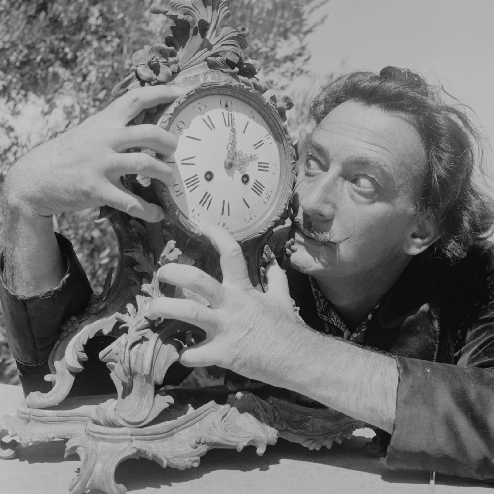 Spanish surrealist artist Salvador Dali (1904 - 1989) clutches an ornate clock at his home in Cadaques on the Costa Brava, Spain, 8th January 1955. Original Publication : Picture Post - 7465 - A Day With Salvador Dali - pub. 1955 (Photo by Charles Hewitt/Picture Post/Hulton Archive/Getty Images)