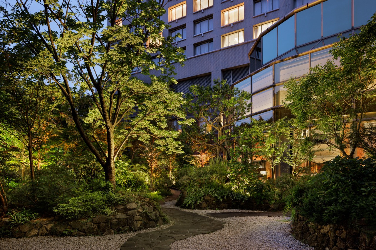 The hotel garden at dusk connects to the lobby, reimagined as an orangery